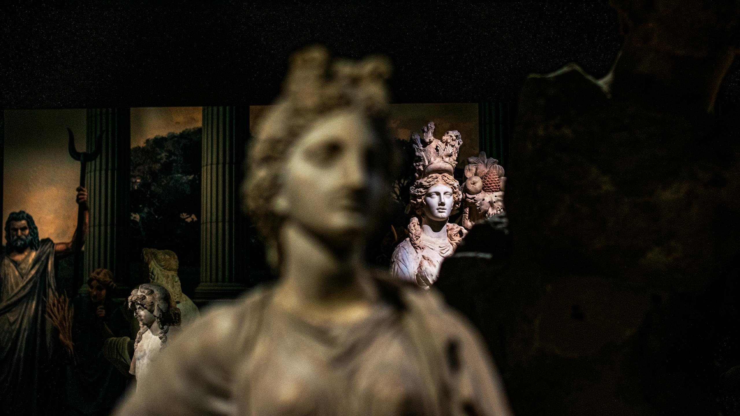 Intricate classical marble statues displayed in a dimly lit museum setting, showcasing artistic craftsmanship.
