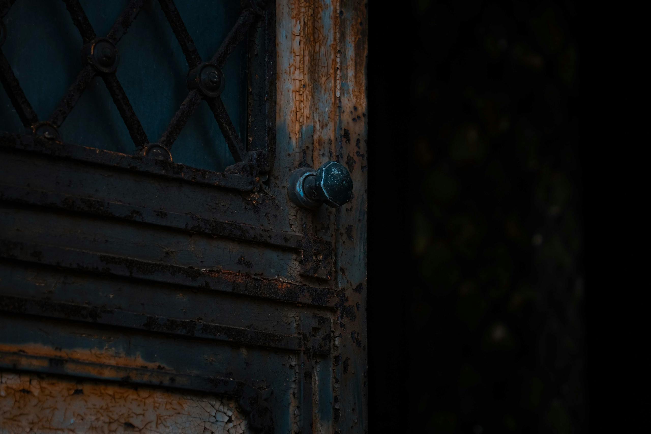 Low angle of weathered aged door with rusted surface and shabby paint of abandoned damaged building