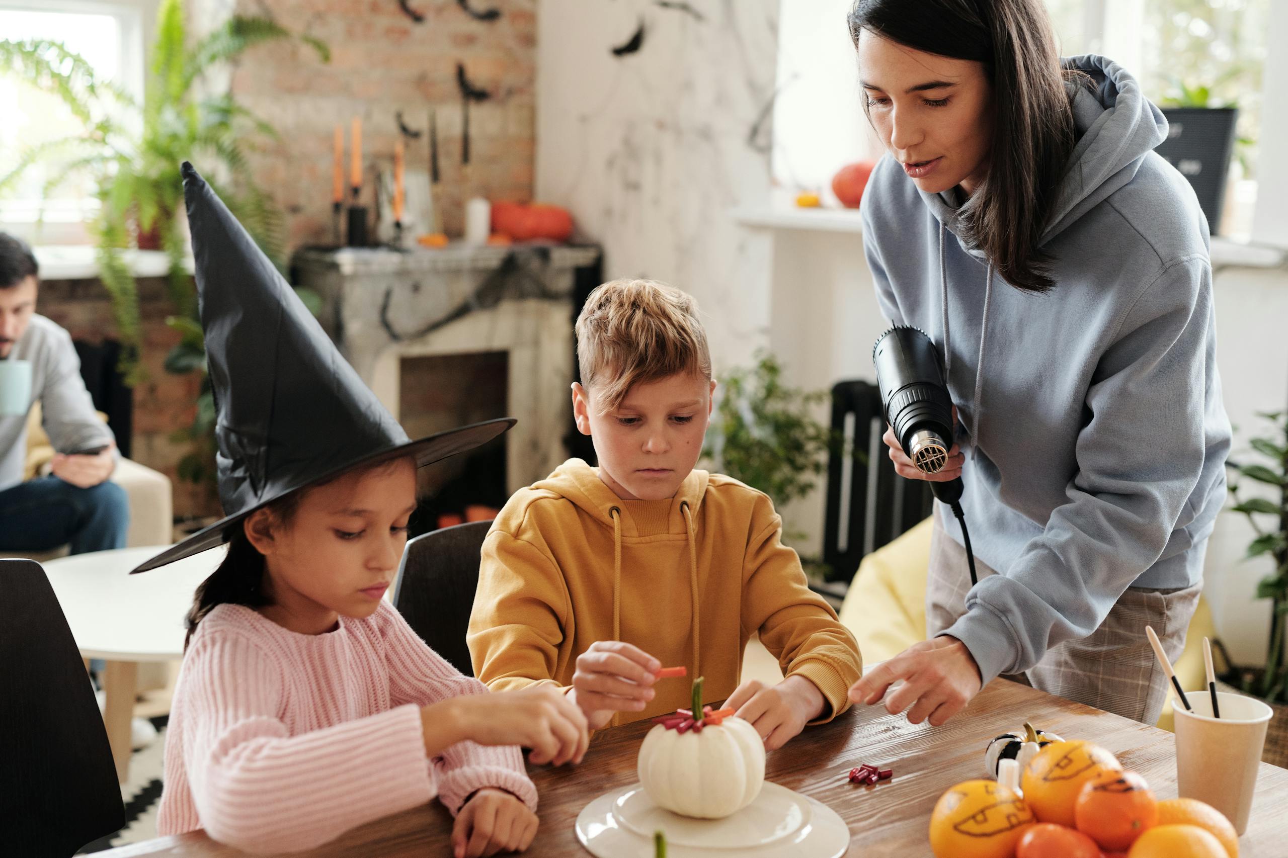 Mother and children decorating Halloween pumpkins together in a cozy home setting.