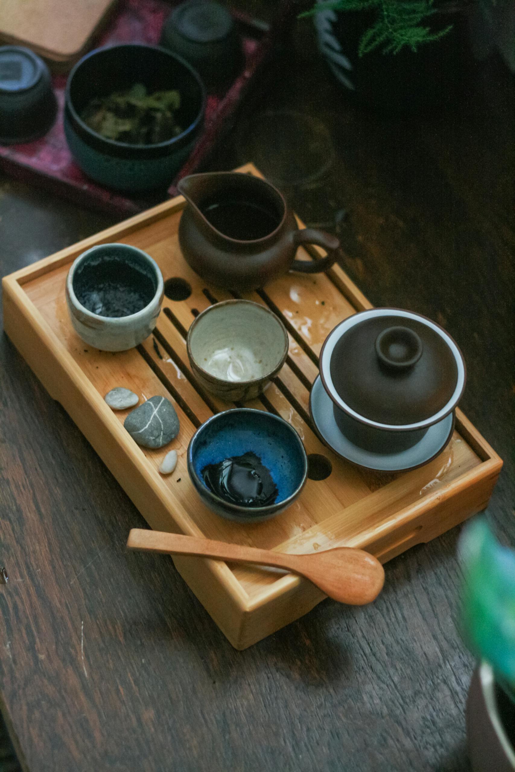 Overhead view of traditional Chinese tea set with various ceramics on wooden tray.