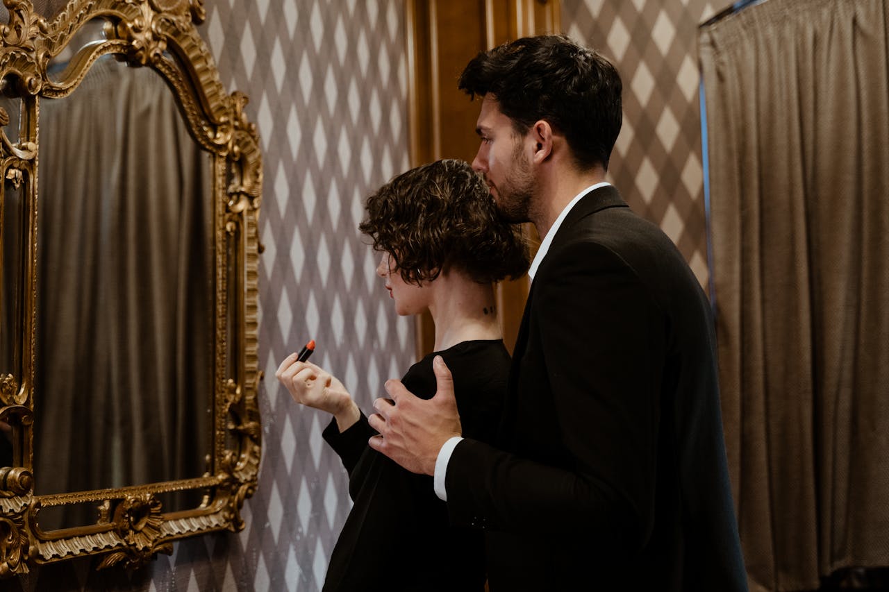 A romantic moment of a couple embracing while getting ready, reflected in a vintage mirror