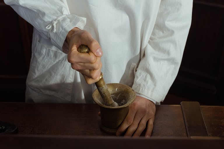 Pharmacist grinding ingredients using a mortar and pestle. Traditional pharmacy preparation.