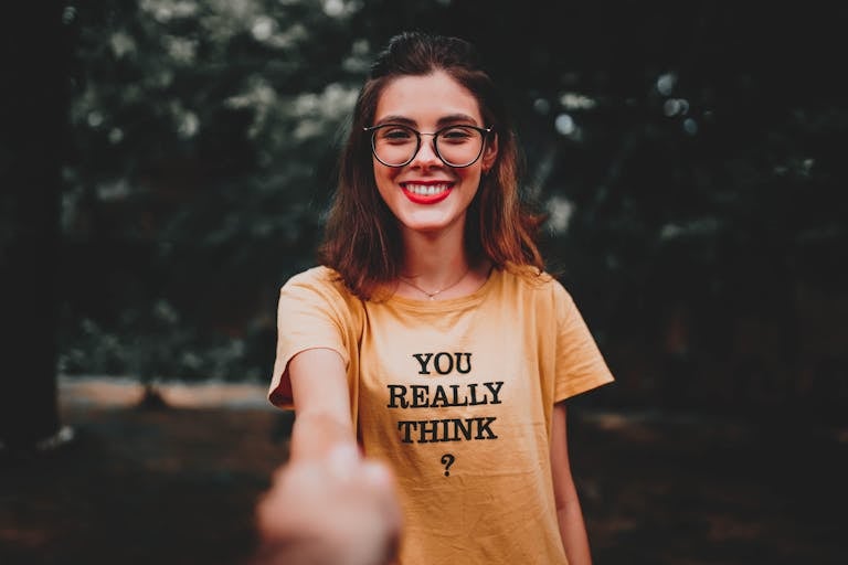 Portrait of a smiling woman with eyeglasses and yellow t-shirt outdoors.