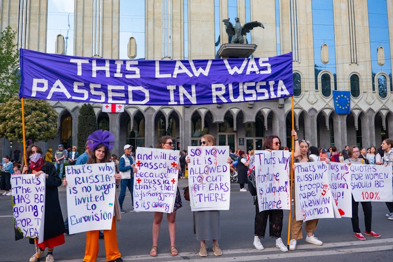 Protestors in Tbilisi rally against Russian laws, holding signs for freedom and independence.