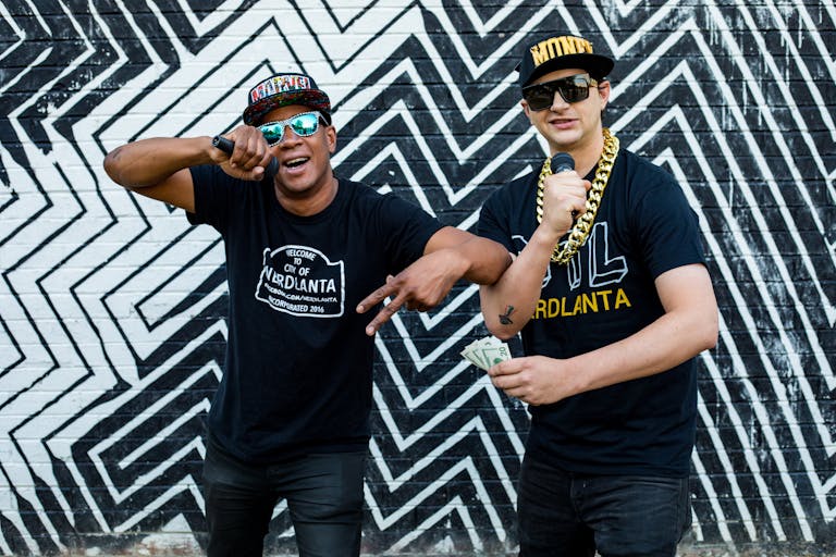 Rap duo performing in front of Atlanta street art, exuding style and energy.