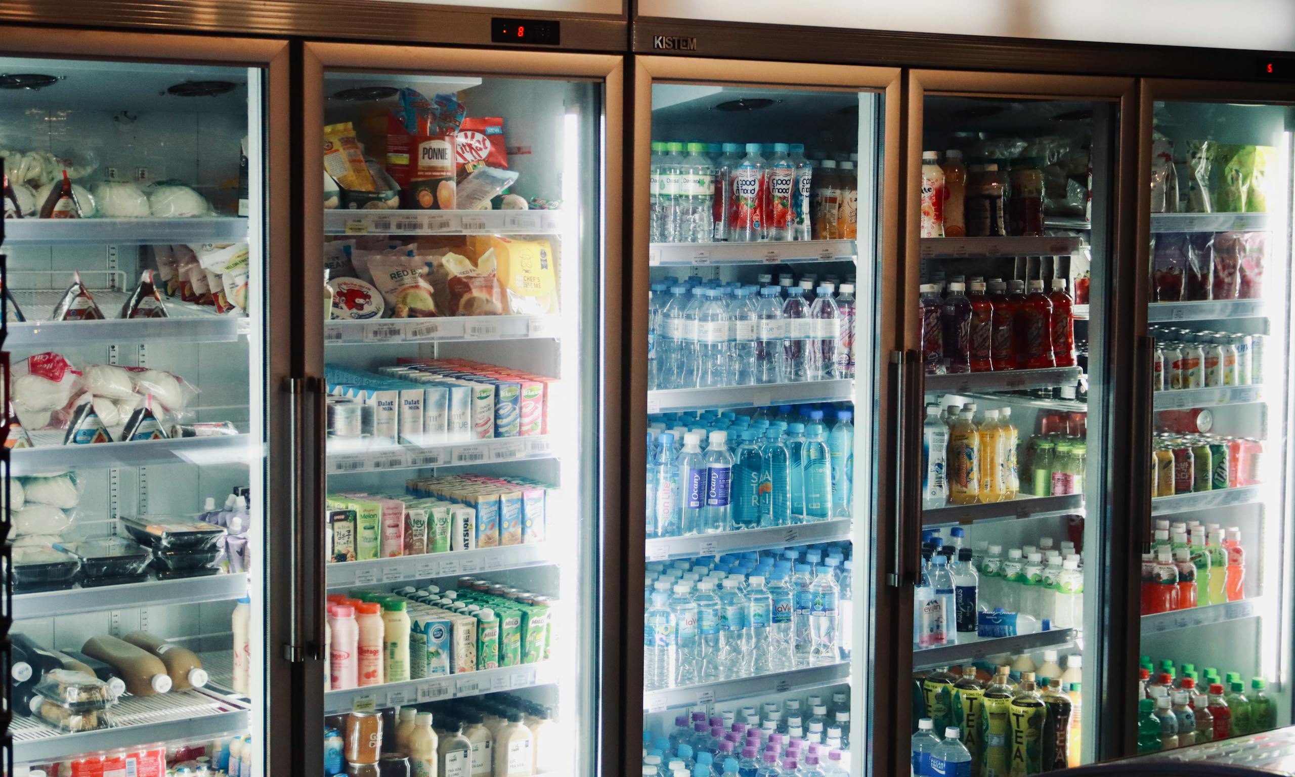 Refrigerator display with various beverages and snacks in a store environment.