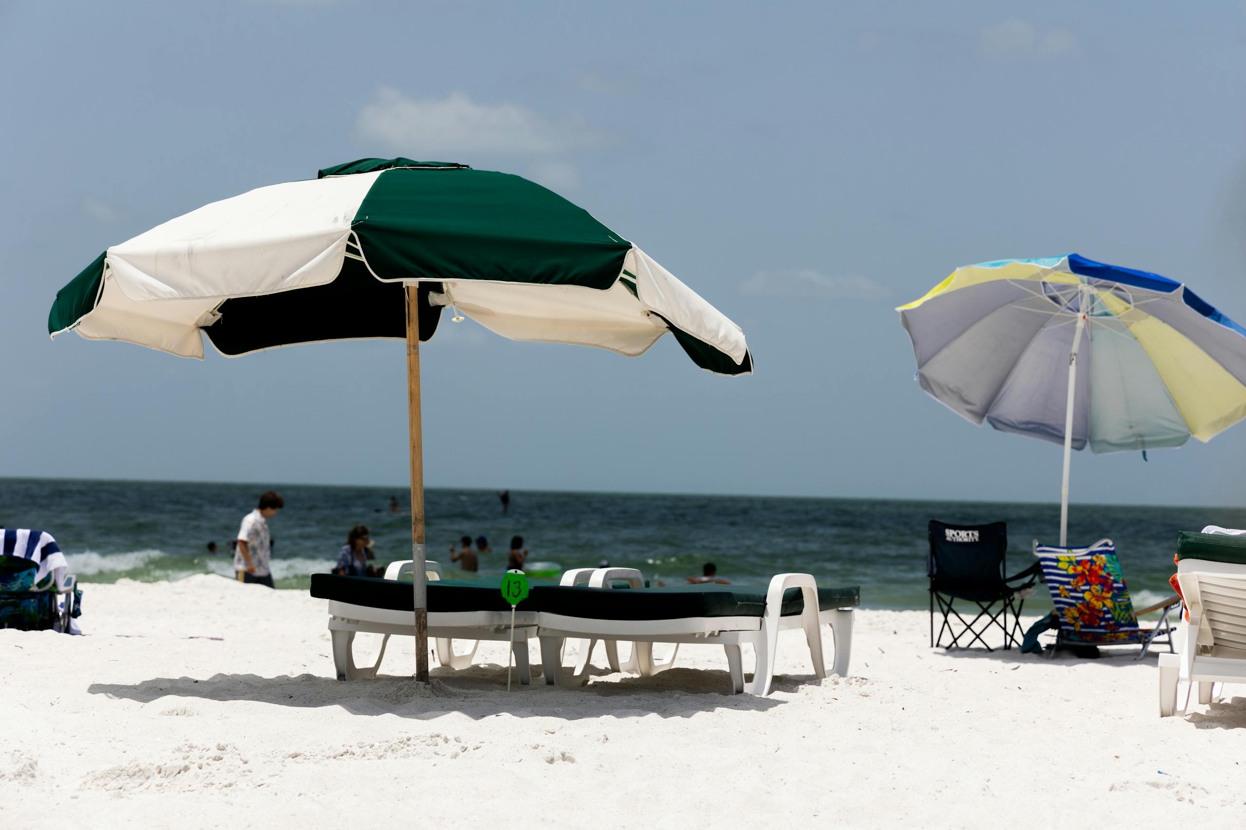 Relaxing beach scene with umbrellas and sunbeds on a sunny, sandy shore.