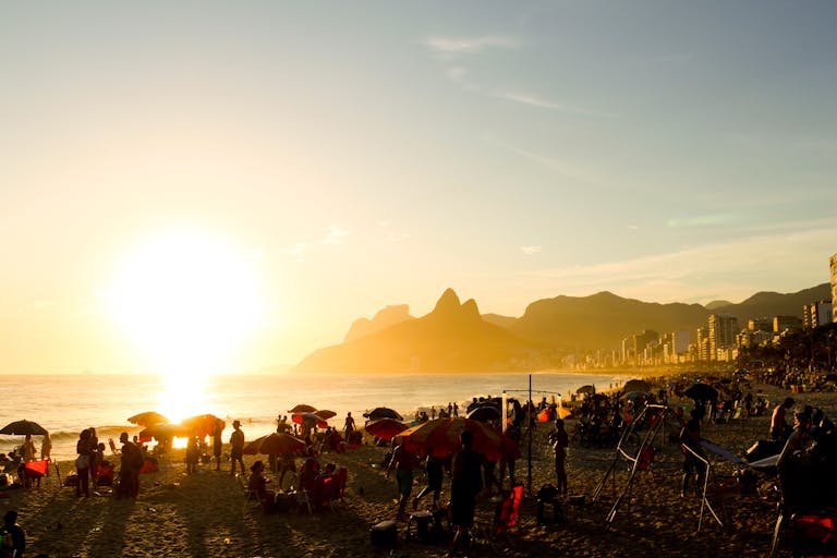 Scenic sunset at Ipanema Beach, Rio de Janeiro, with crowds and vibrant atmosphere.