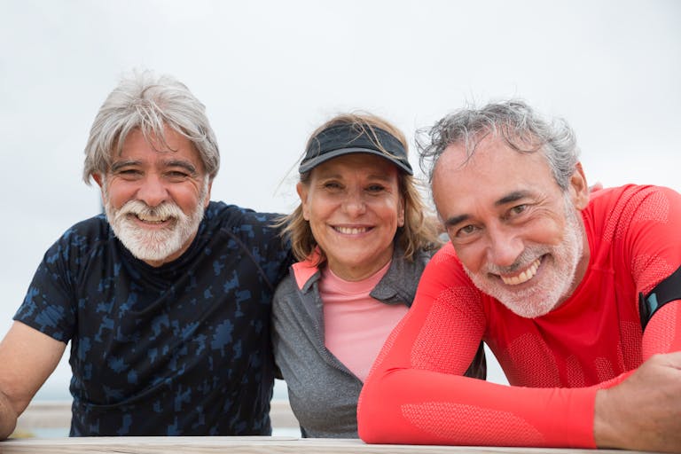 Senior friends in Portugal smiling and enjoying an outdoor fitness activity.
