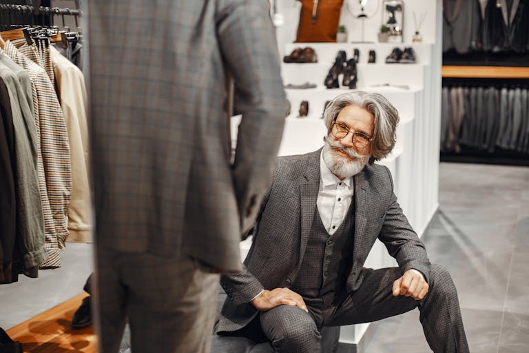Senior man in a store choosing elegant suits, showcasing refined style and fashion.