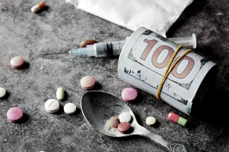Symbolic representation of drug addiction and financial cost with pills and money.