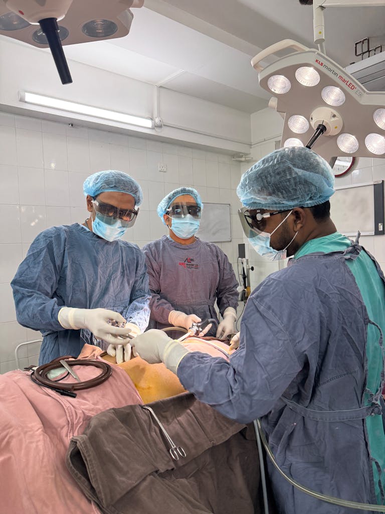 Team of surgeons in operating room performing surgery under bright lights, focused on patient.