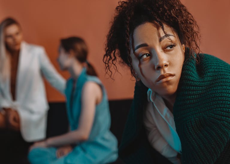 Thoughtful woman in focus with diverse background, highlighting social issues.