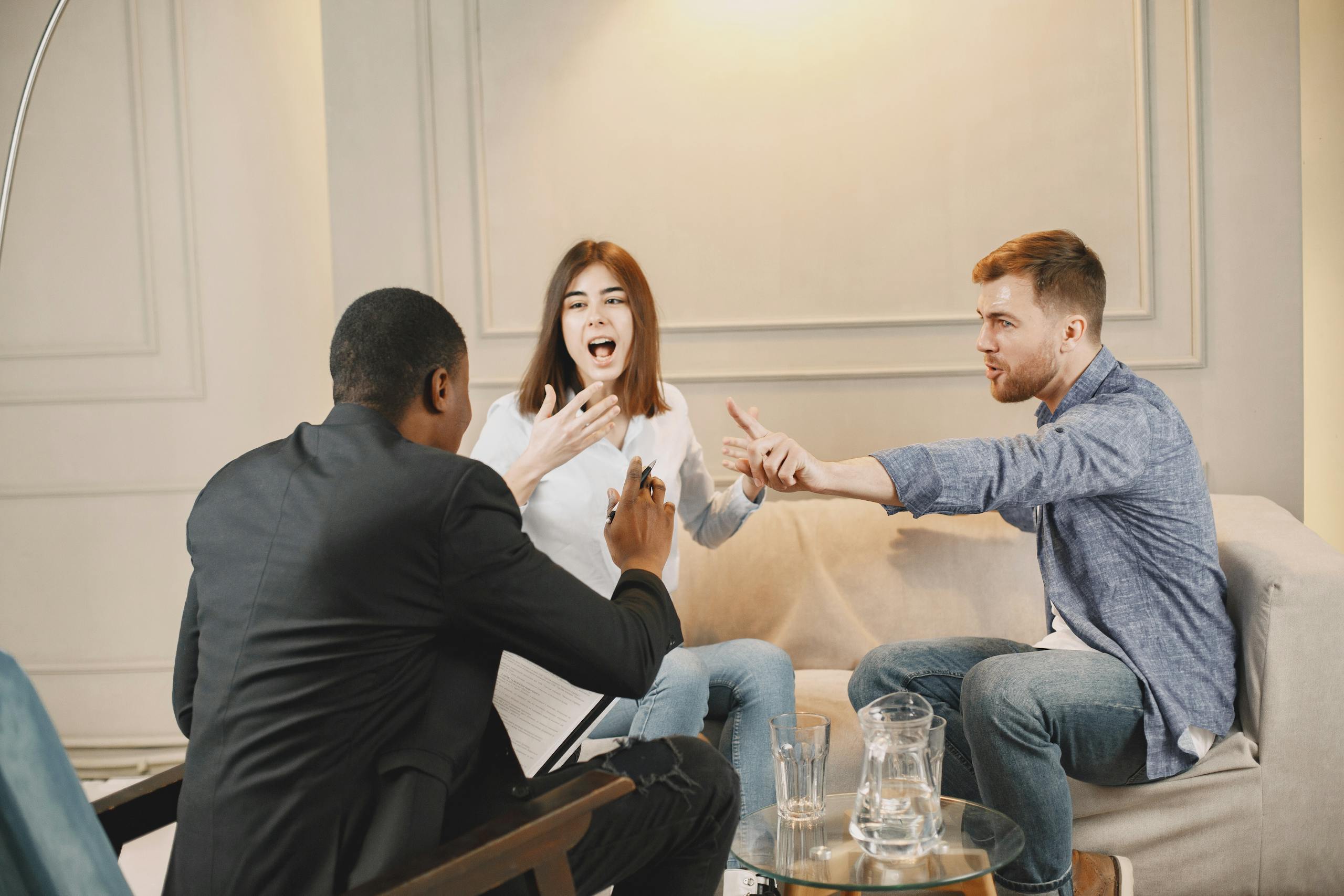 Three adults engaged in a lively discussion indoors, showcasing active communication and expression.