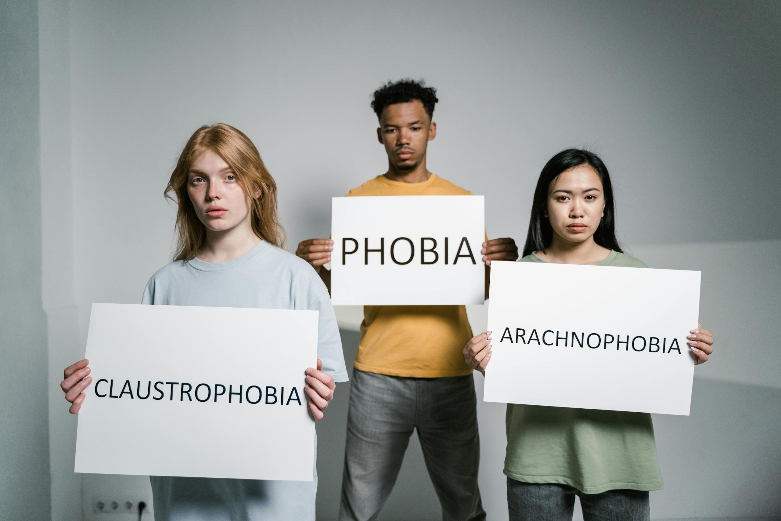 Three individuals demonstrate common phobias: arachnophobia, claustrophobia, and general fear.