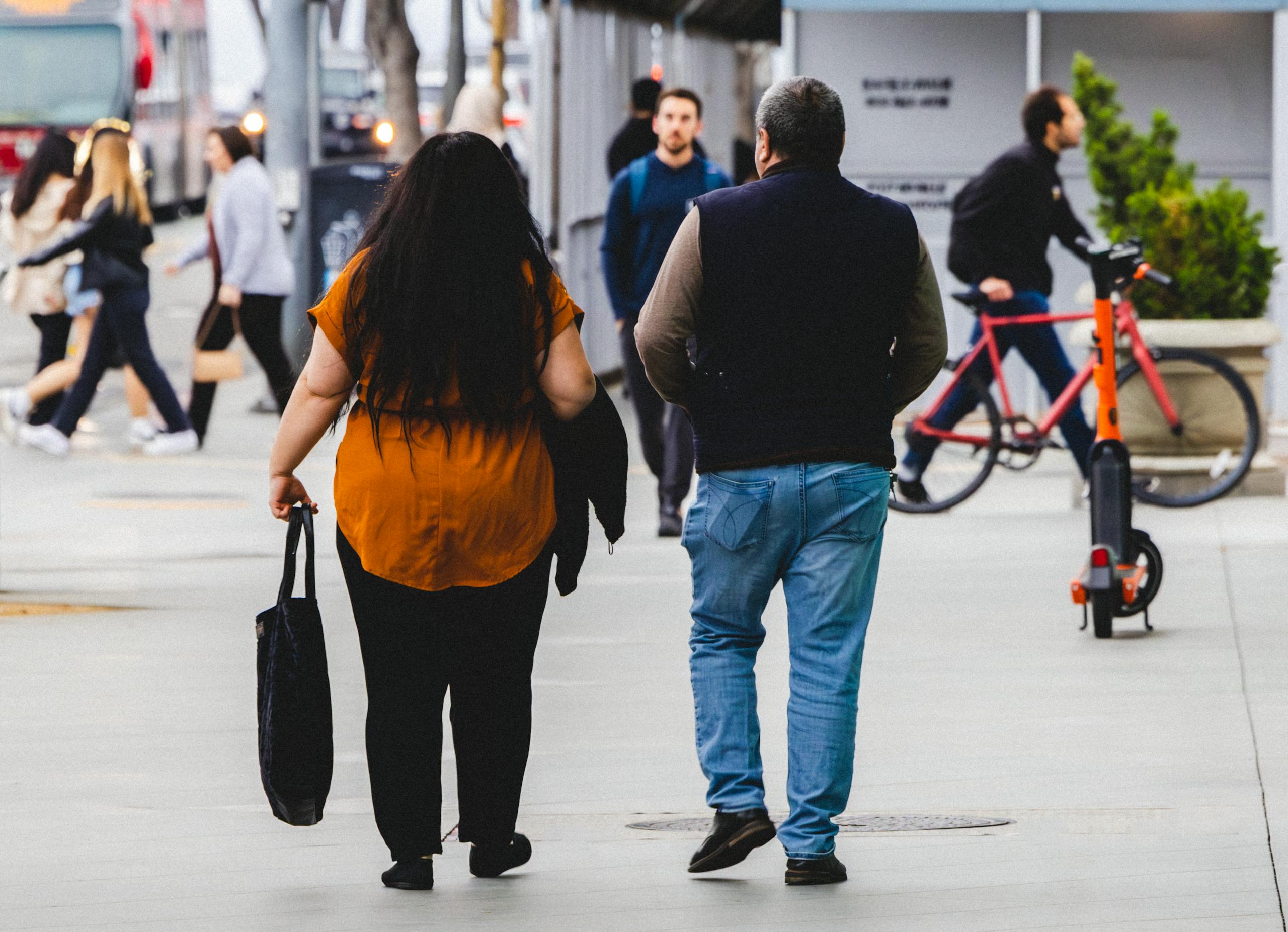 Two adults walking together on a bustling city sidewalk, capturing the essence of urban life.