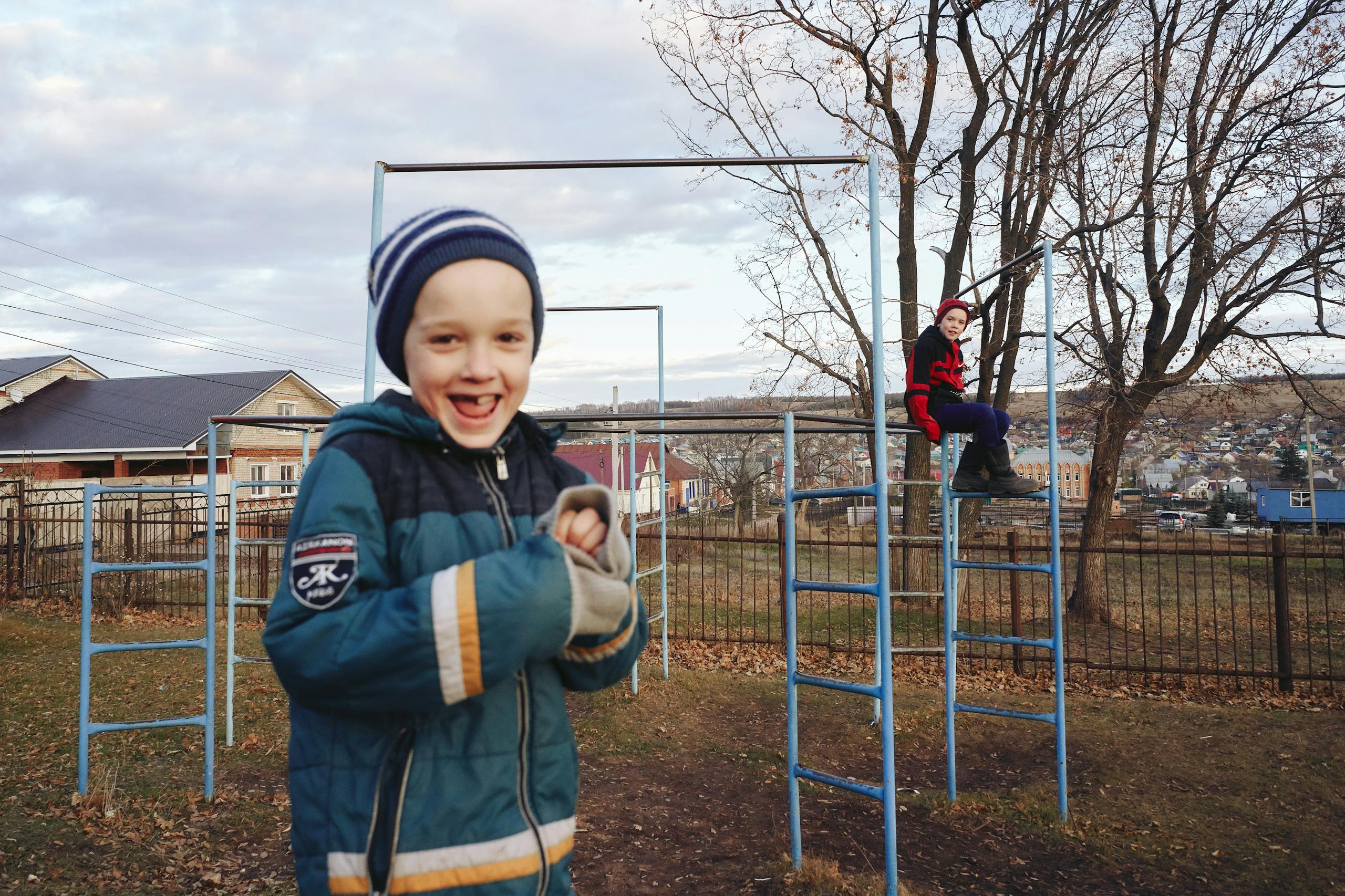 Two boys having fun in an outdoor playground during an autumn day.