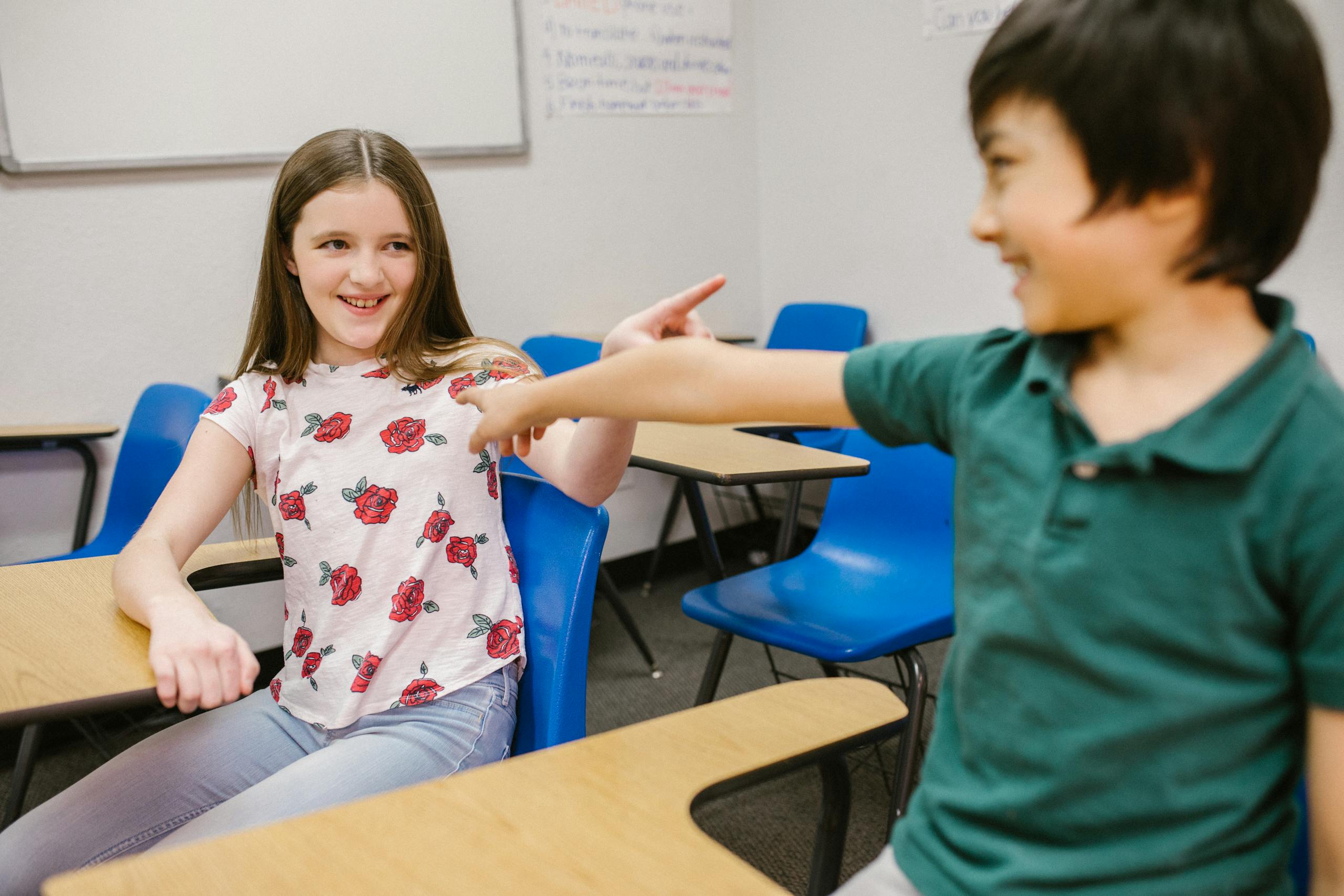 Two children playfully interacting in their classroom environment, showcasing positive energy.