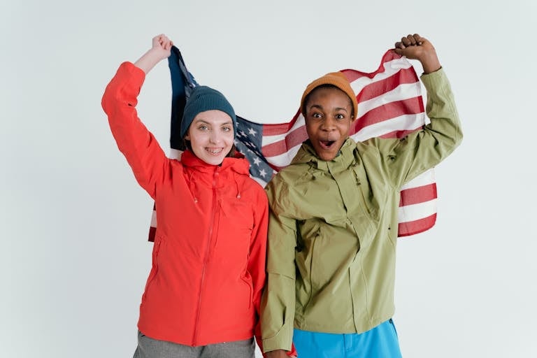 Two friends joyfully holding an American flag, expressing friendship and celebration.