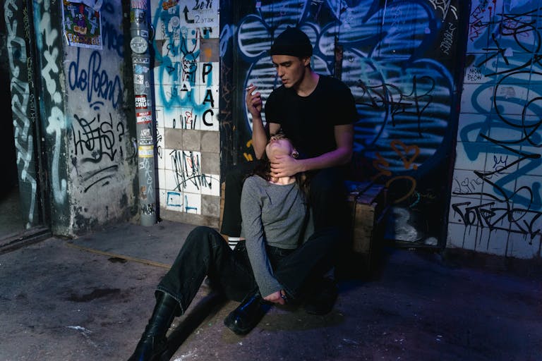 Two people interacting in an urban setting with vibrant graffiti on the walls.