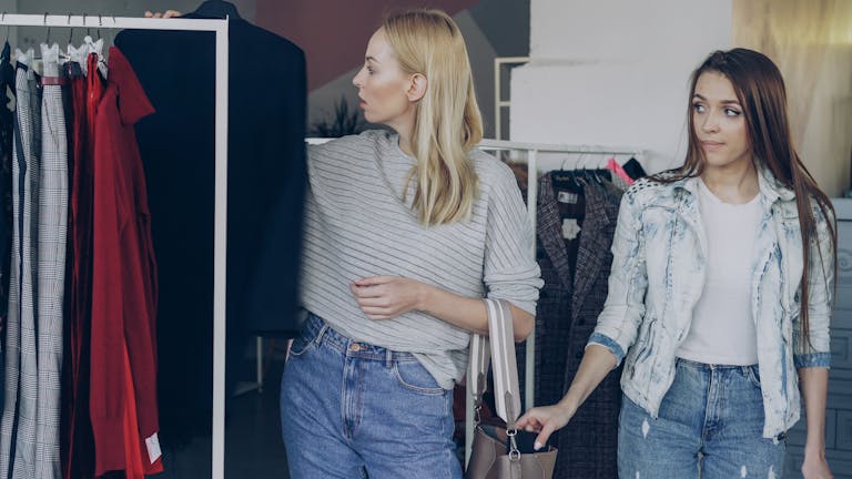 Two women browsing clothing in a fashion store, exploring styles.