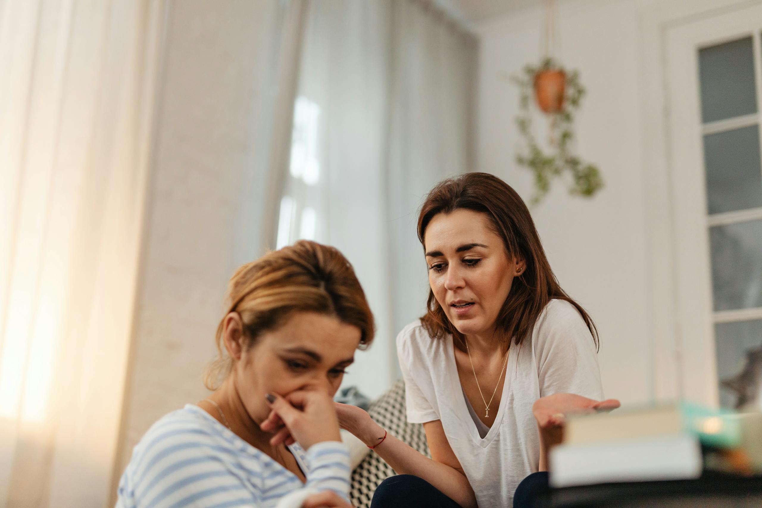 Two women engaging in emotional support and communication indoors.