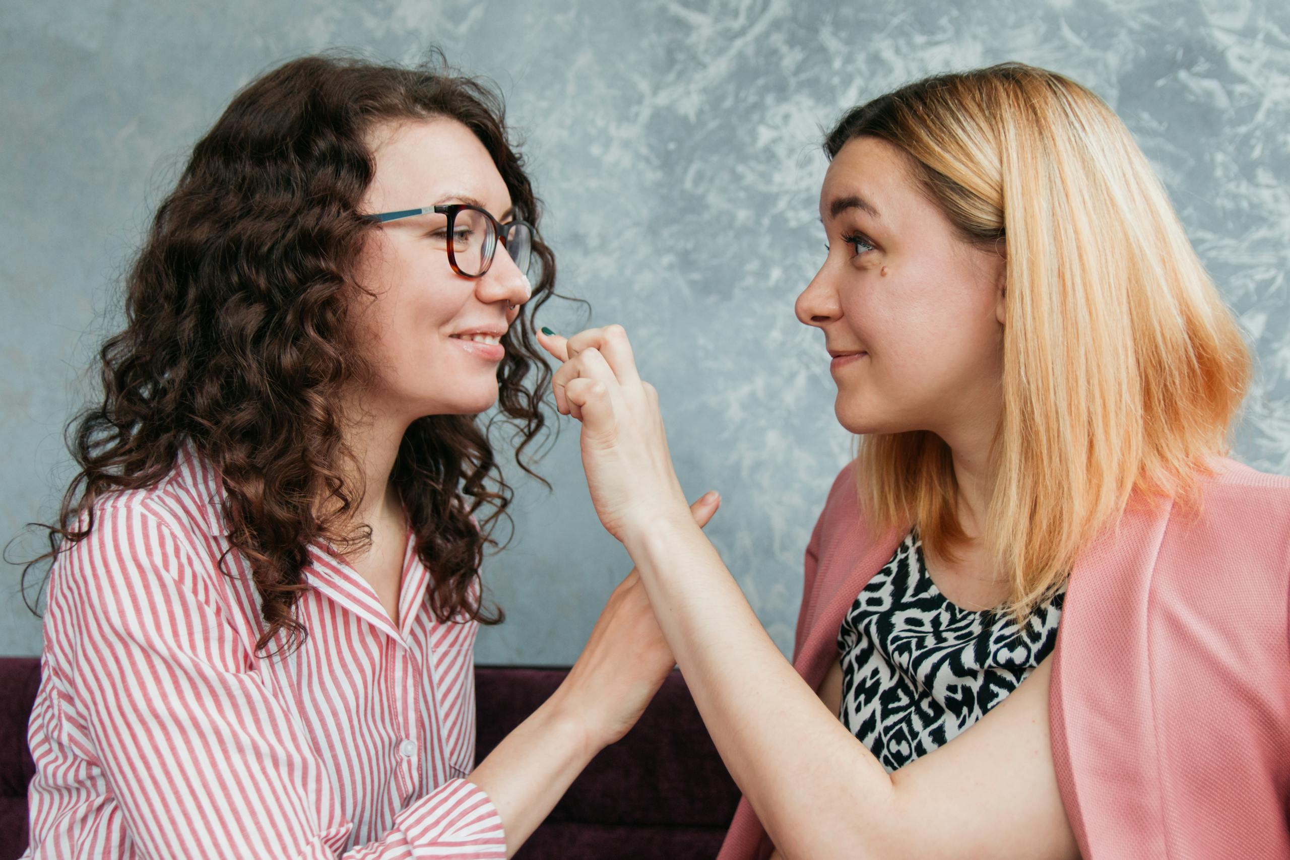 Two women smiling and bonding indoors, showcasing friendship and connection.