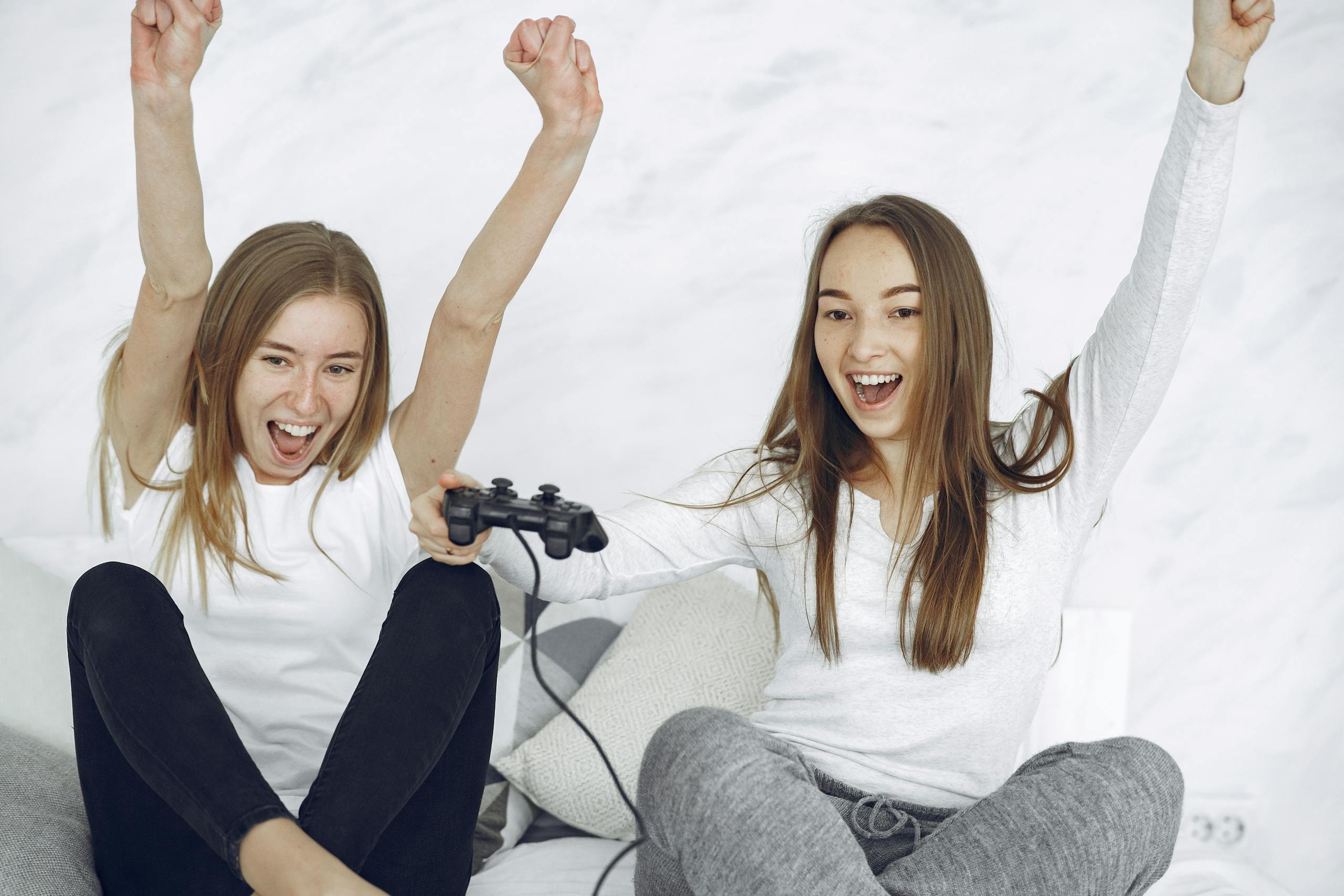 Two young adults joyfully celebrating a victory while playing a video game indoors.