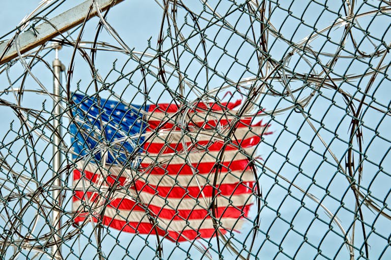 USA flag seen through barbed wire, symbolizing freedom and protection