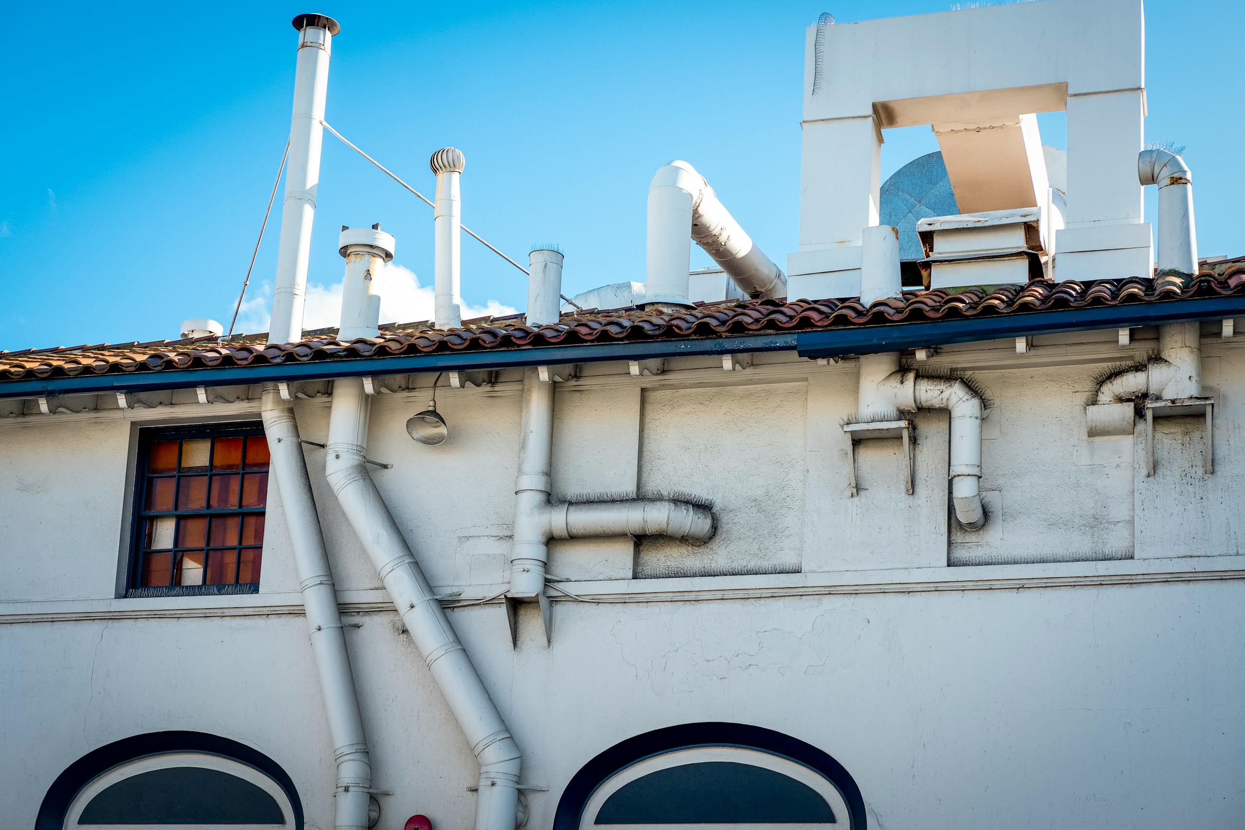 White building with chimneys and ventilation pipes on a clear day.