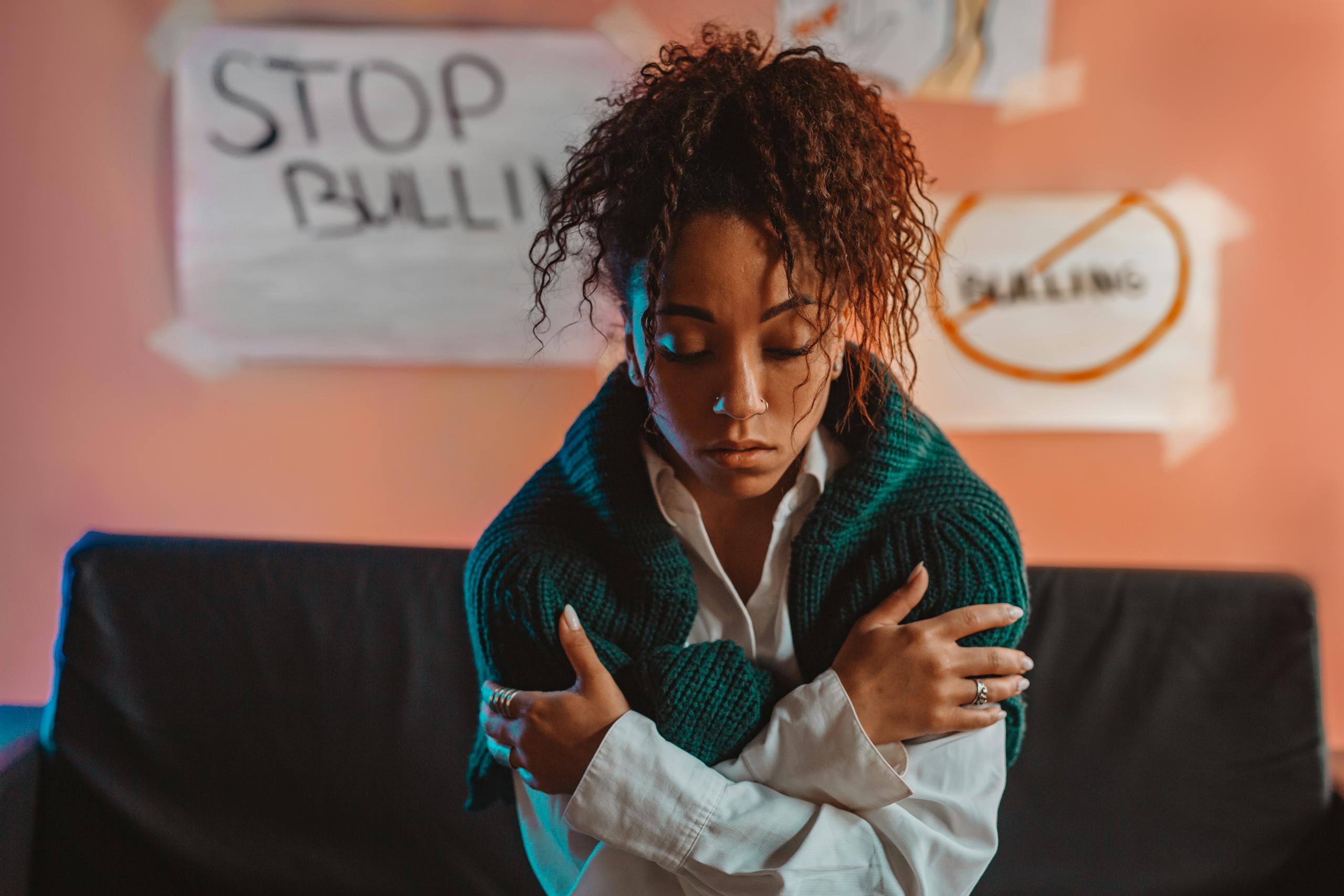 Woman with curly hair and crossed arms, surrounded by anti-bullying signs.
