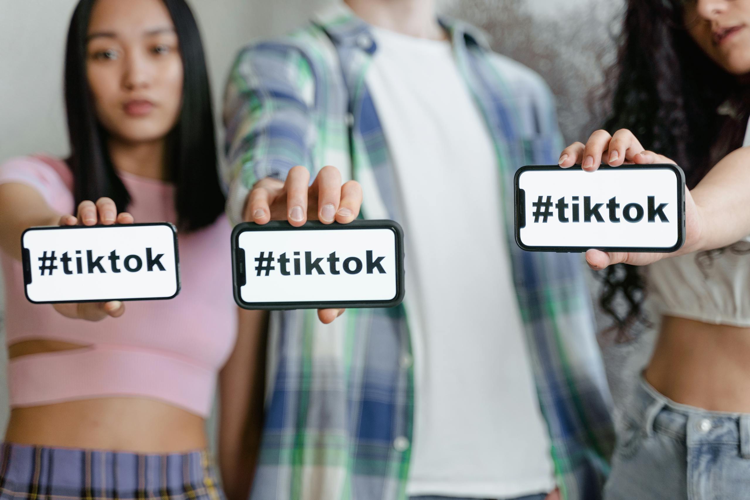Young adults holding smartphones with TikTok hashtag, showcasing social media engagement.