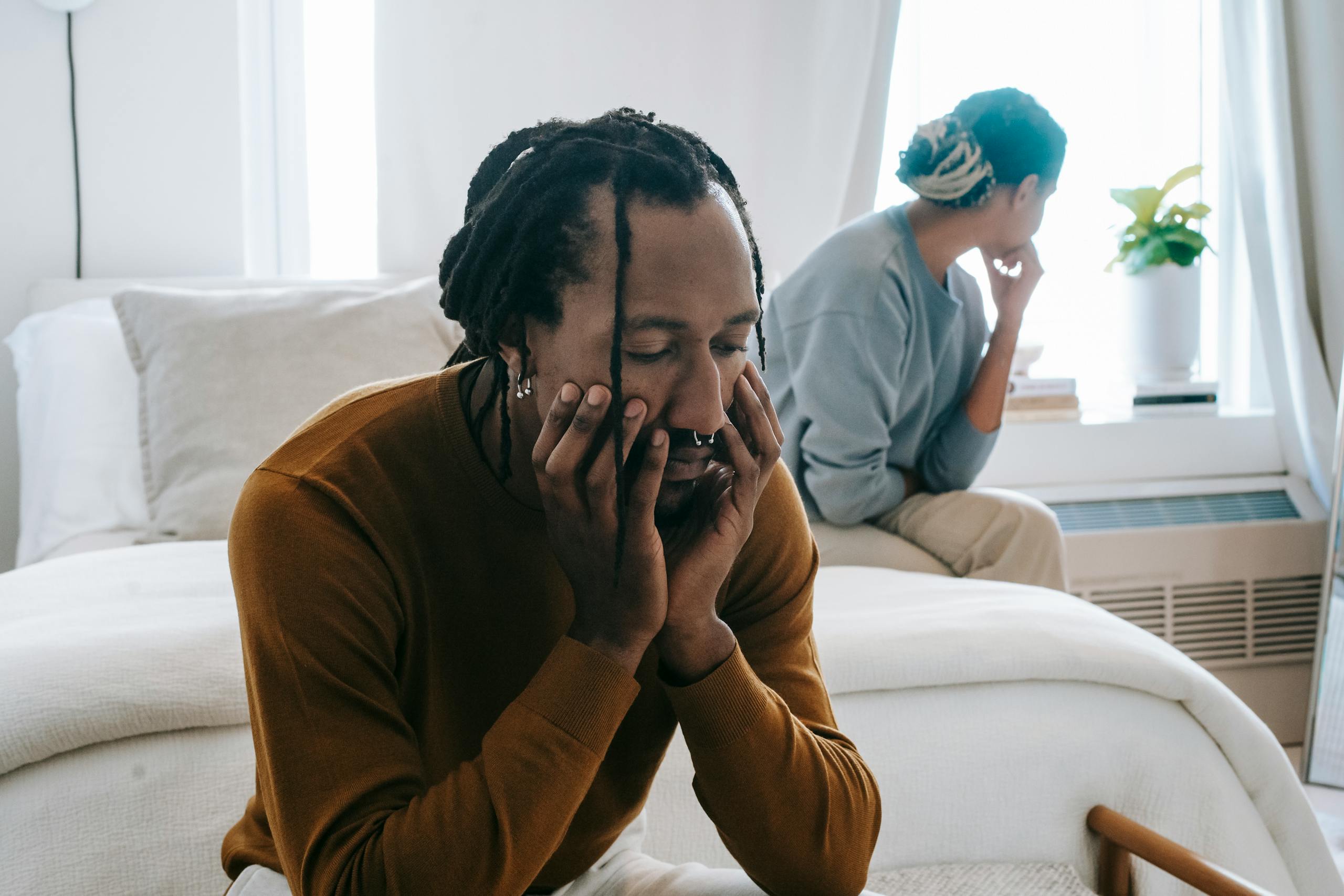 Young black couple spending time in bedroom and thinking while wearing casual outfit at home in daylight