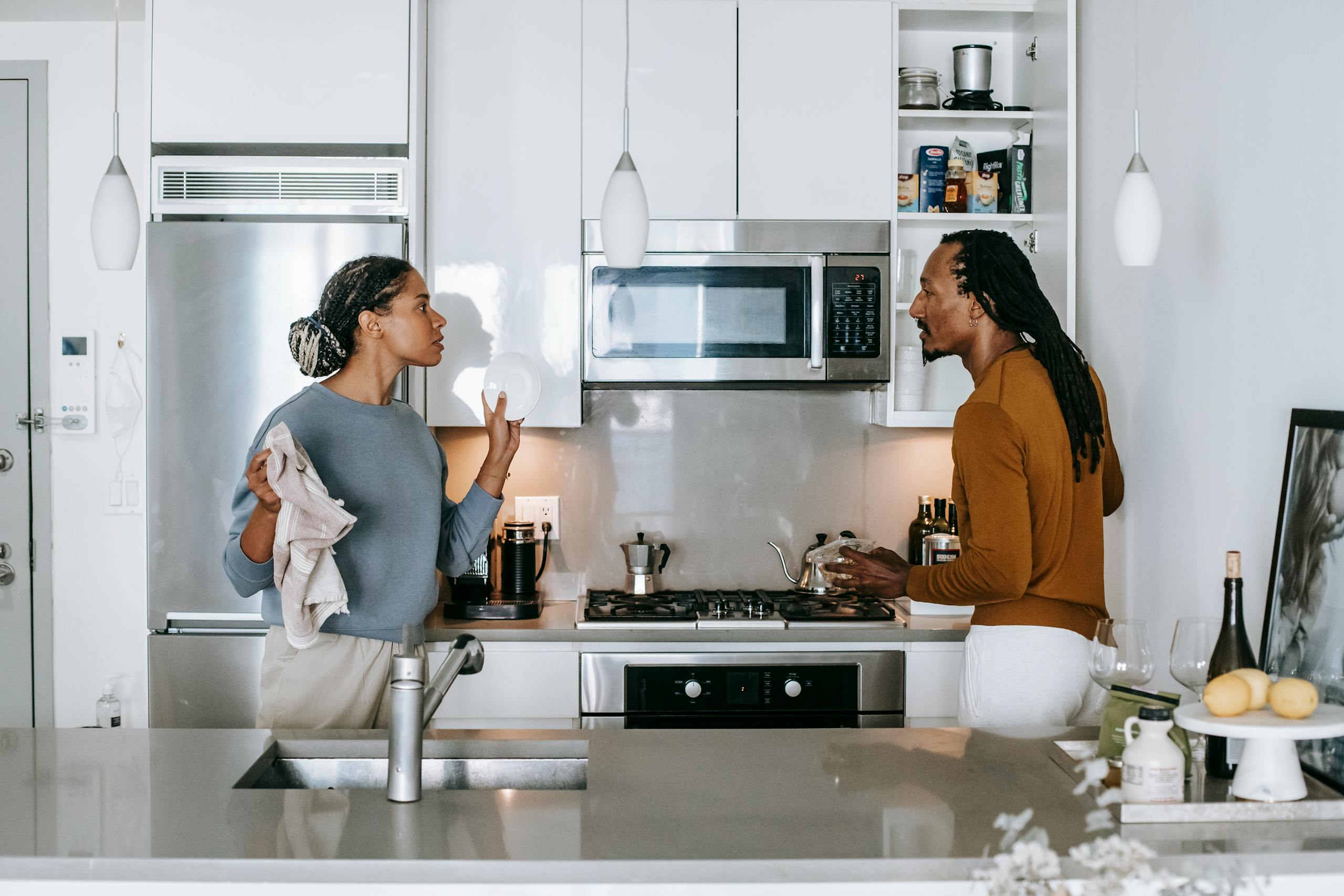 Young black woman talking to annoyed male partner while looking at each other during quarrel in house