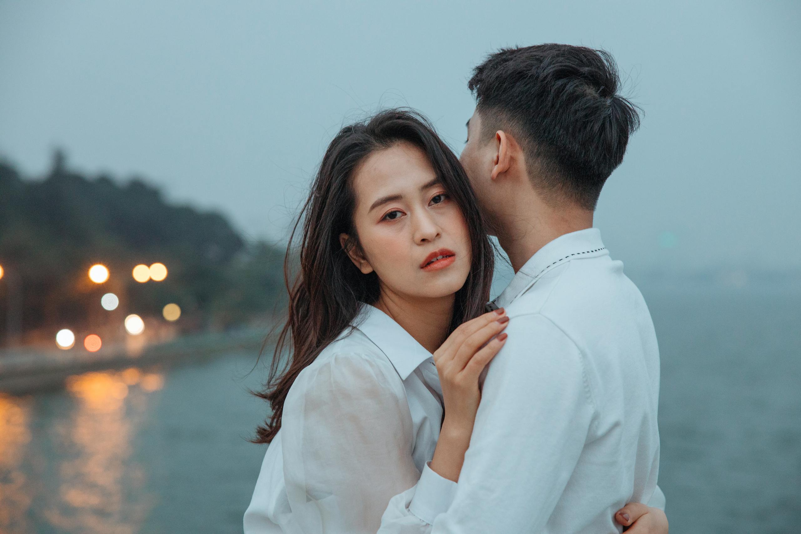 Young couple embracing near a lake, creating a romantic and serene scene.