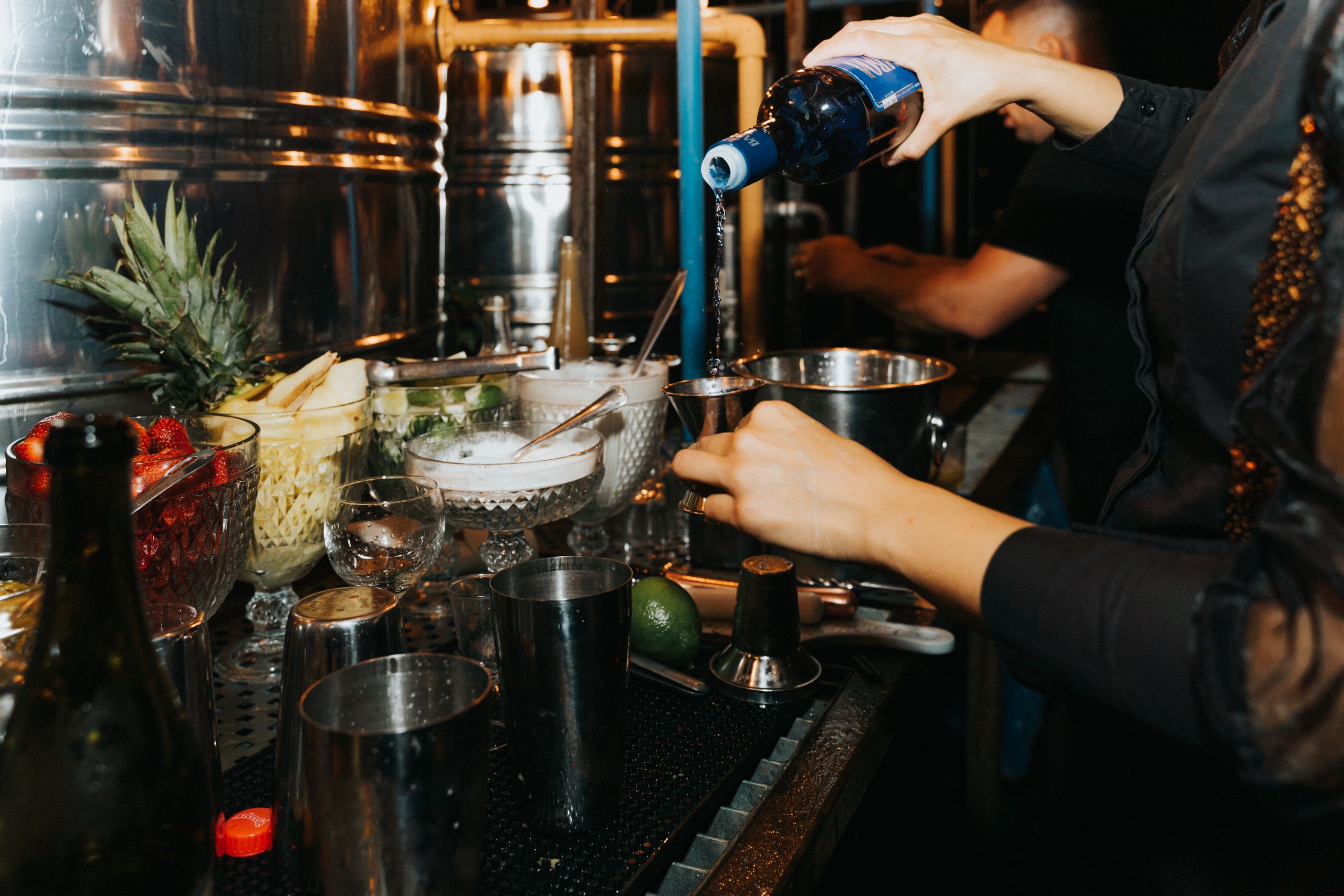 A bartender skillfully pouring drinks amidst a lively bar setup in a nightclub.