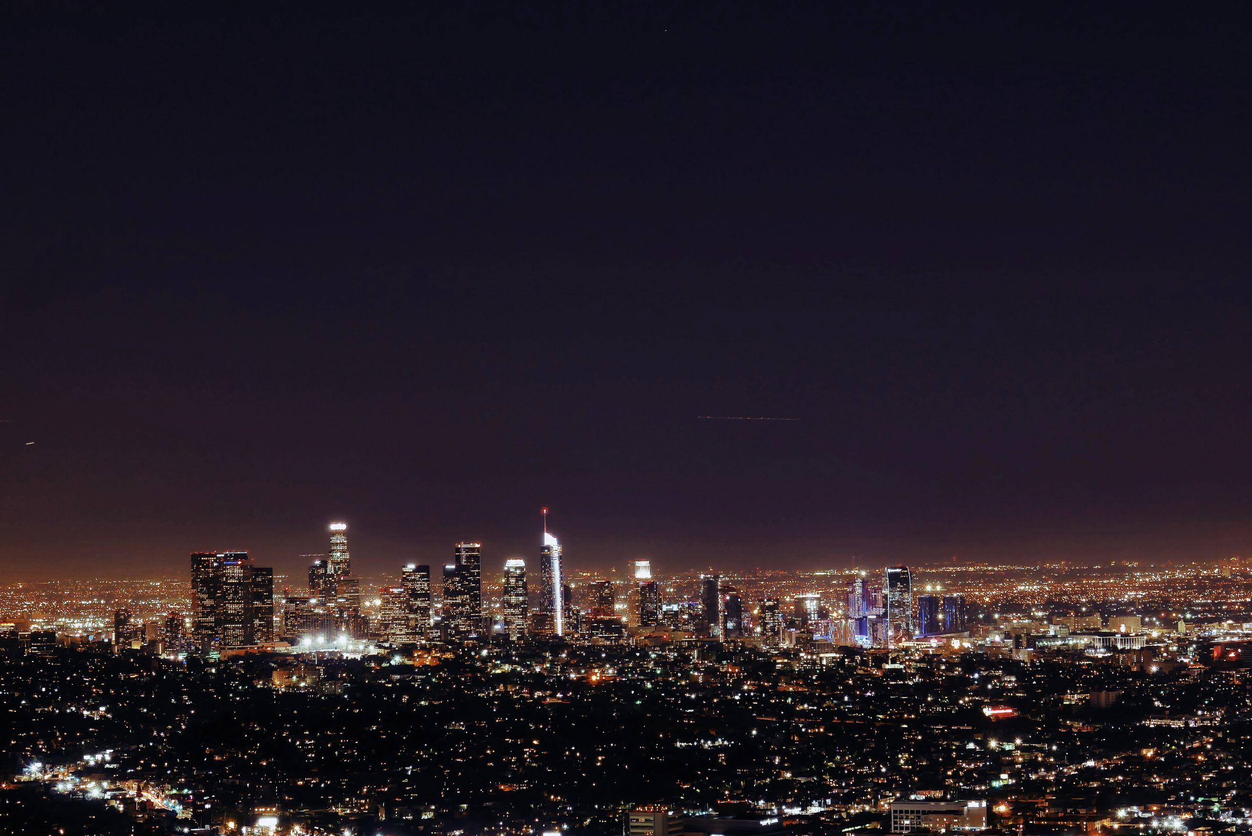 A breathtaking aerial night view of Los Angeles with modern skyscrapers illuminated under the starry sky.