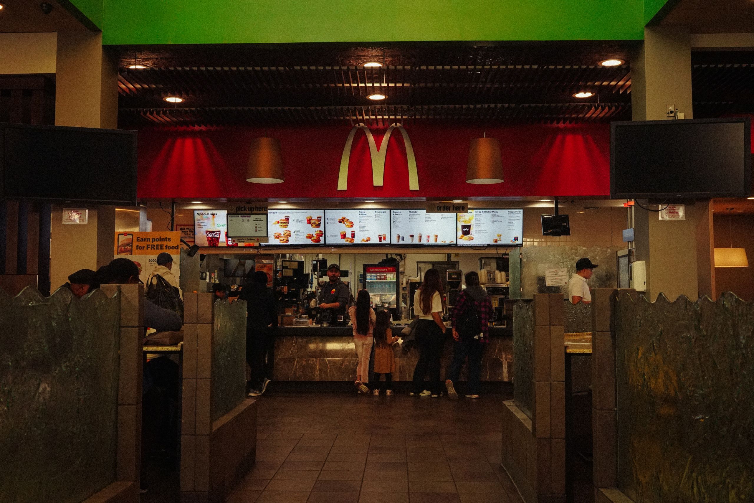 A bustling scene at a McDonald's restaurant counter with customers and staff in an indoor setting.