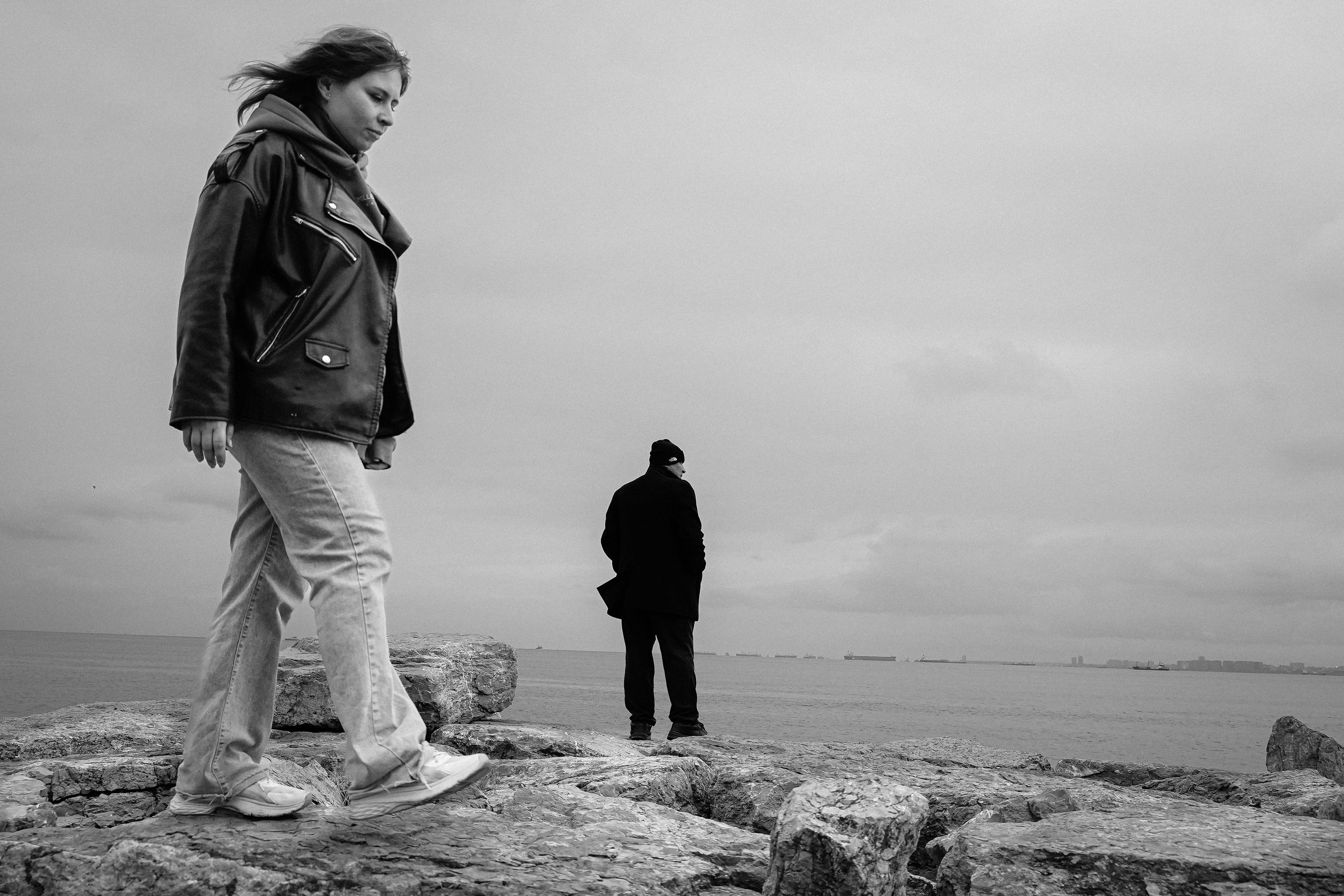 A captivating black and white photo of two people by the İstanbul shoreline, capturing the city's essence.