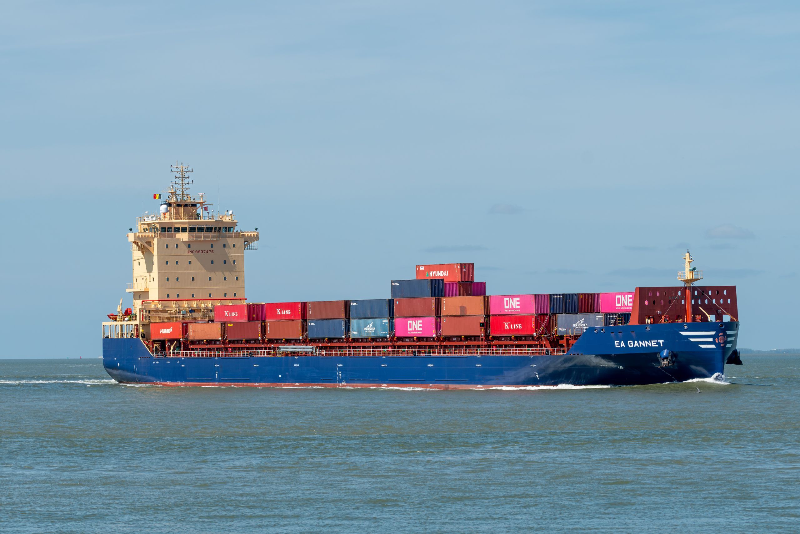 A cargo ship transporting colorful containers across a calm sea on a clear day.