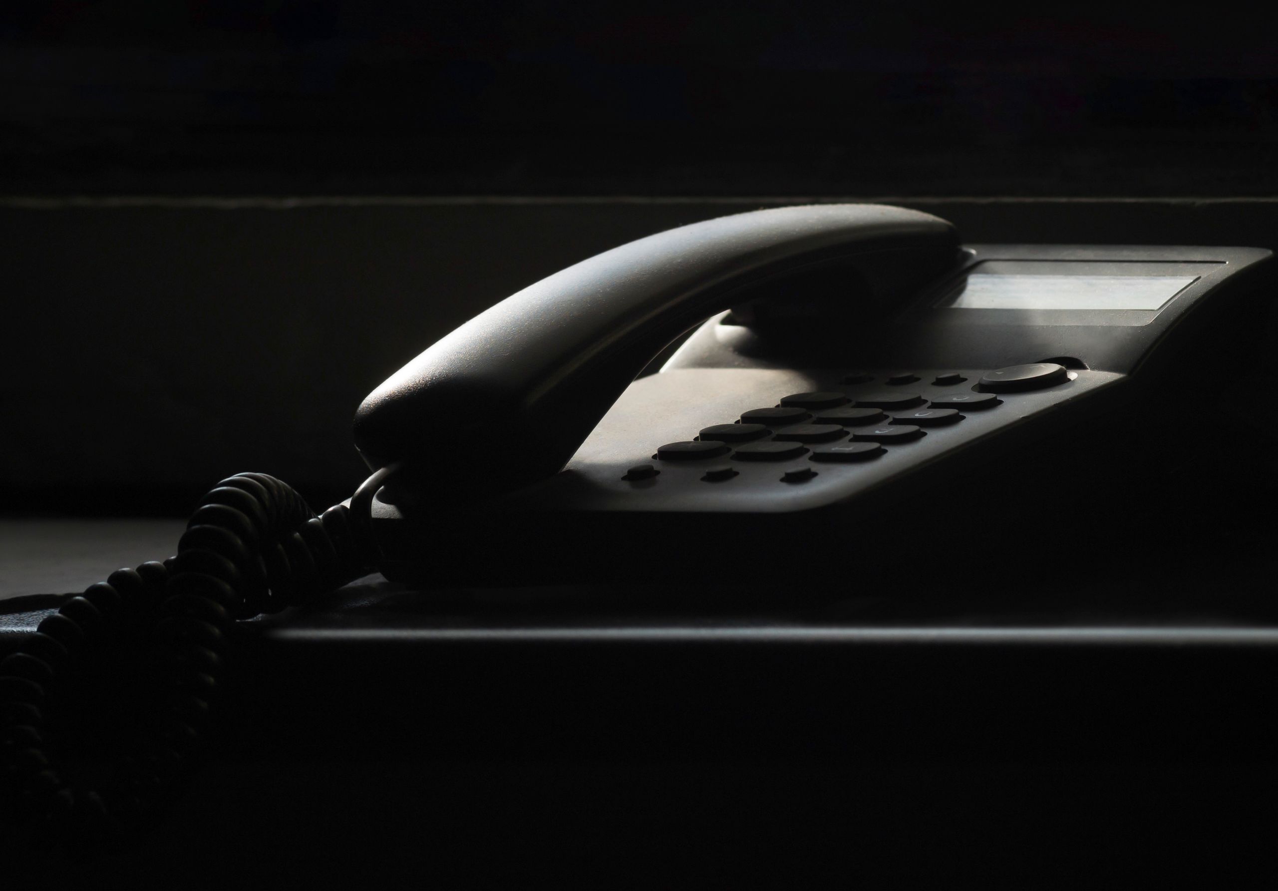 A close-up of a vintage landline phone in dramatic shadow lighting, evoking nostalgia.
