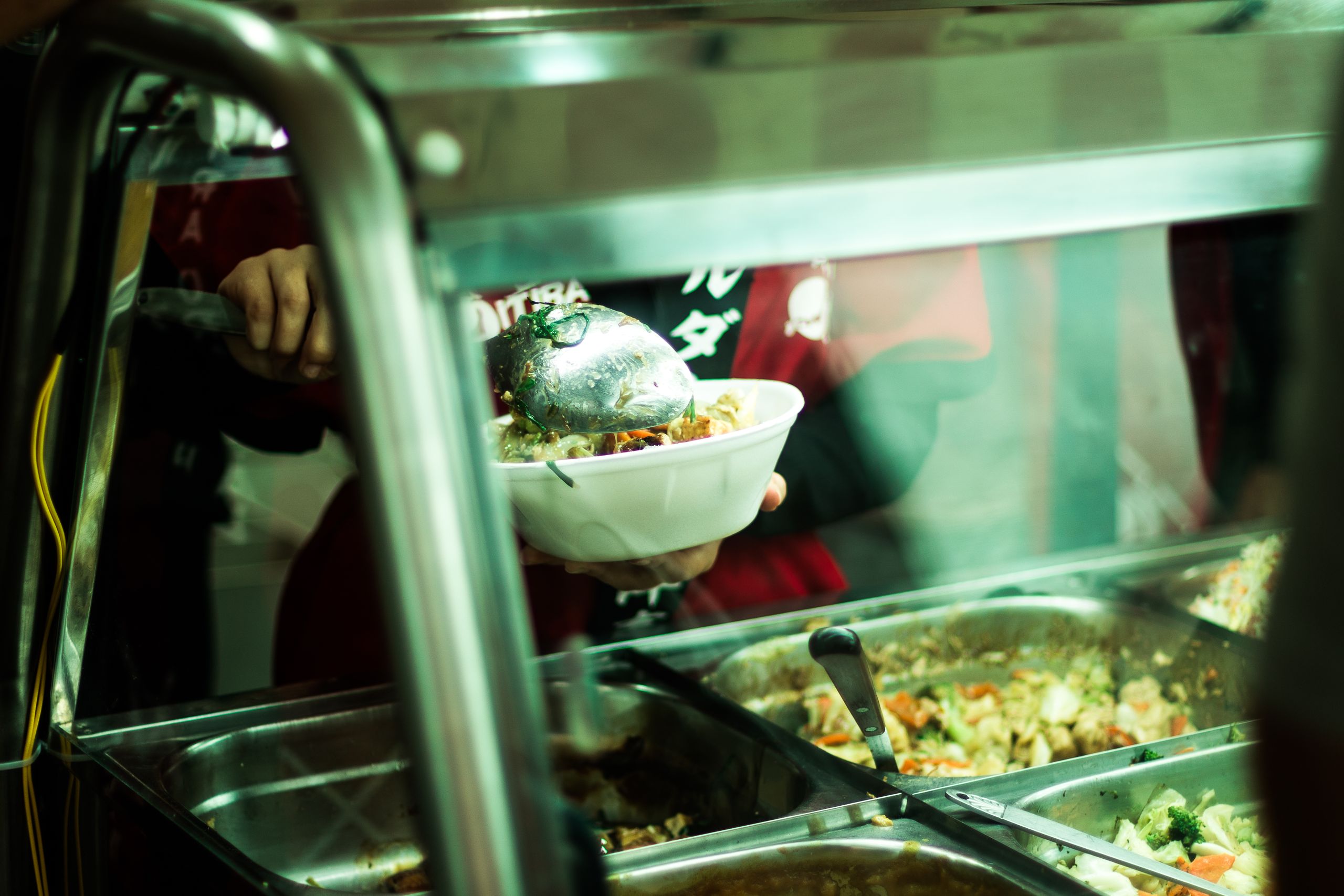 A close-up of food being served in a popular S&atilde;o Paulo food stand, showcasing vibrant ingredients.