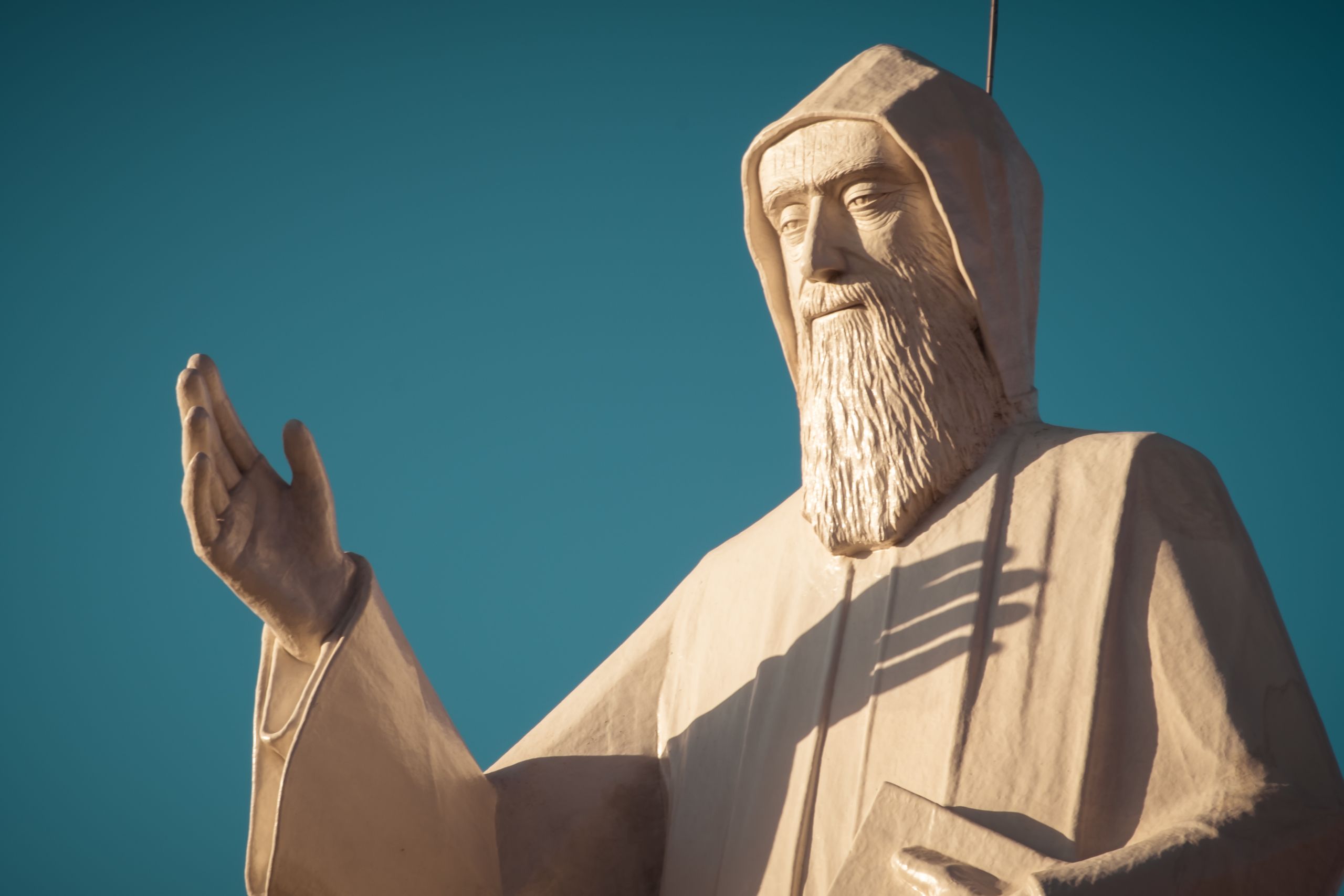 A close-up view of Saint Charbel statue against a clear blue sky, symbolizing peace and spirituality.