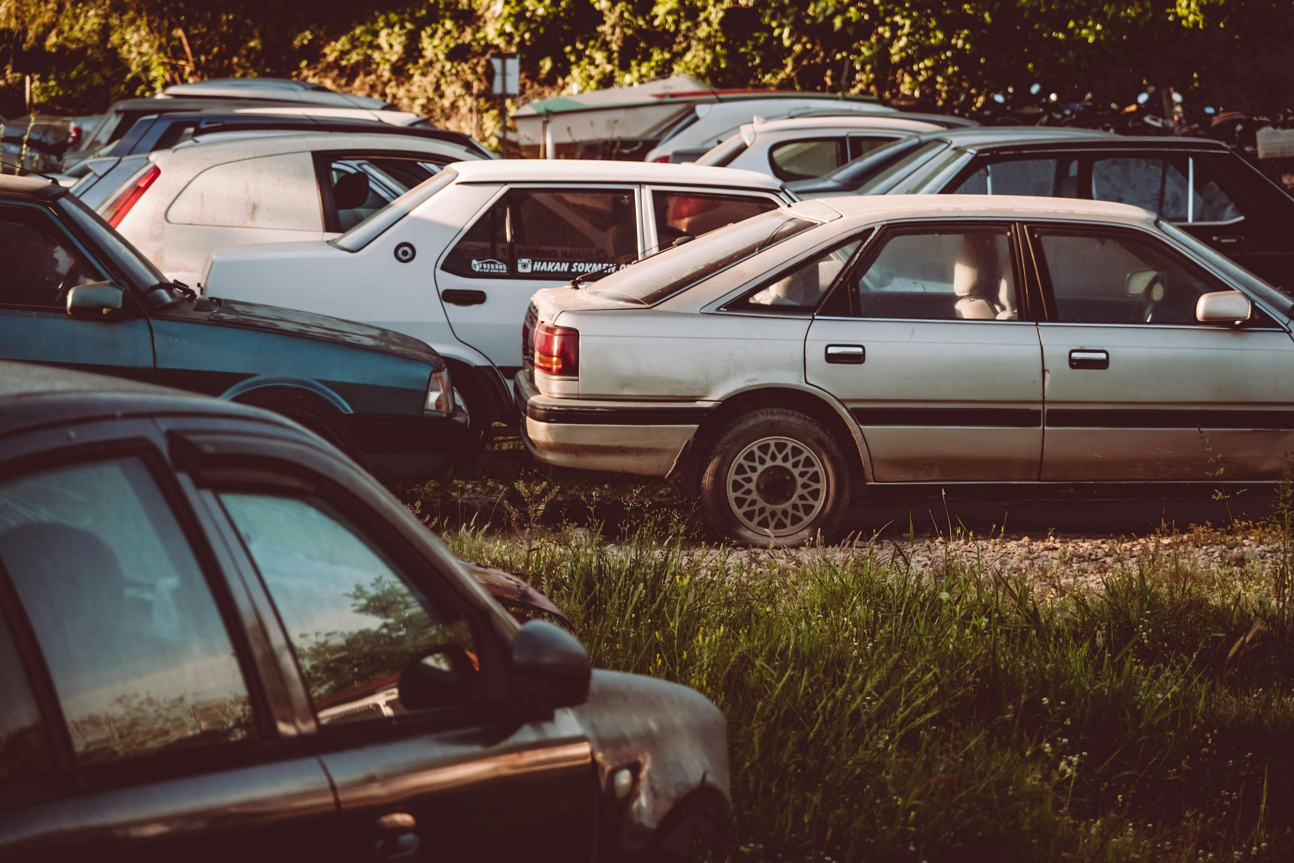 A collection of abandoned, rusting cars in an overgrown field, capturing a vintage feel.