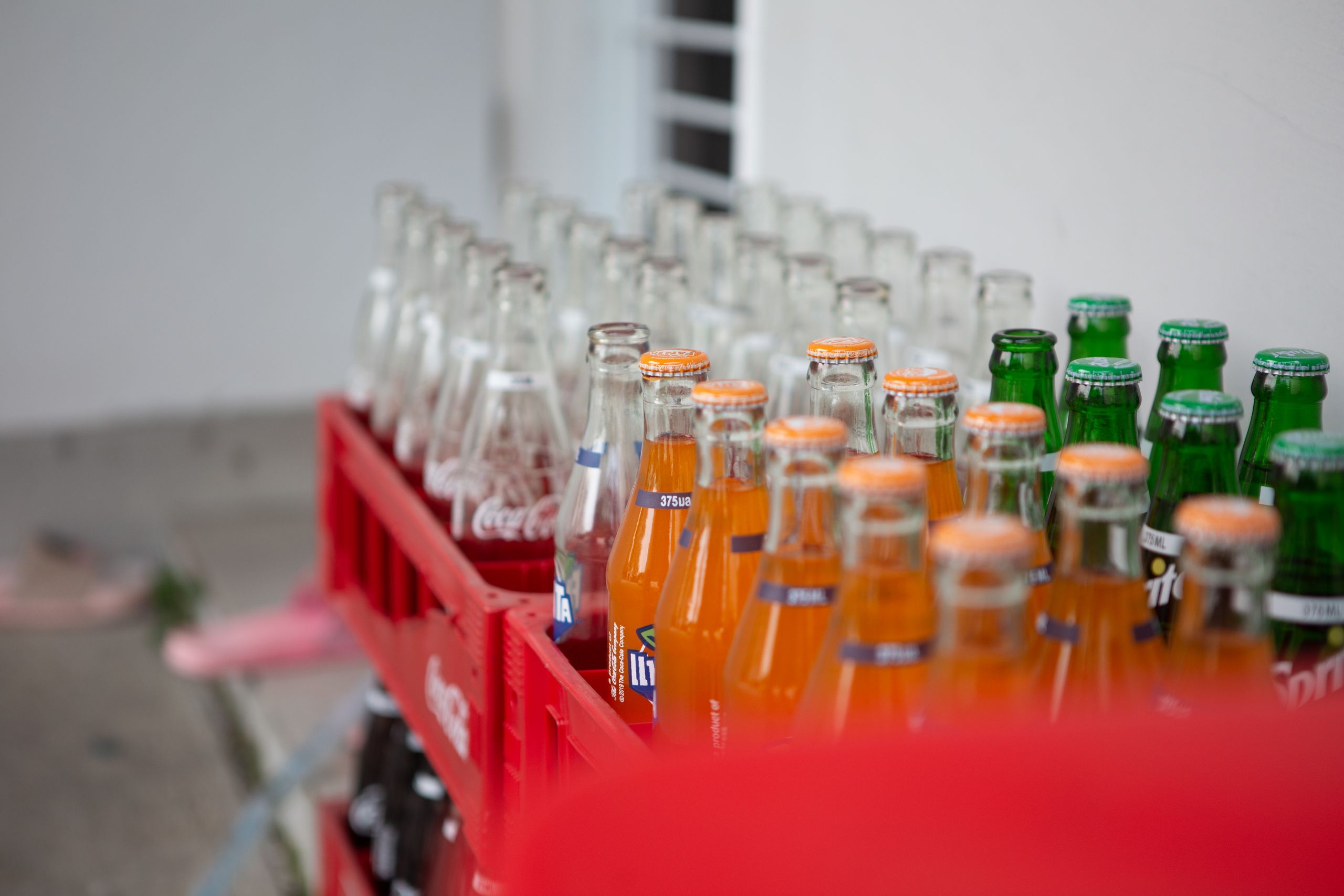 A collection of various bottled soft drinks in red crates, showcasing vibrant colors and popular brands.