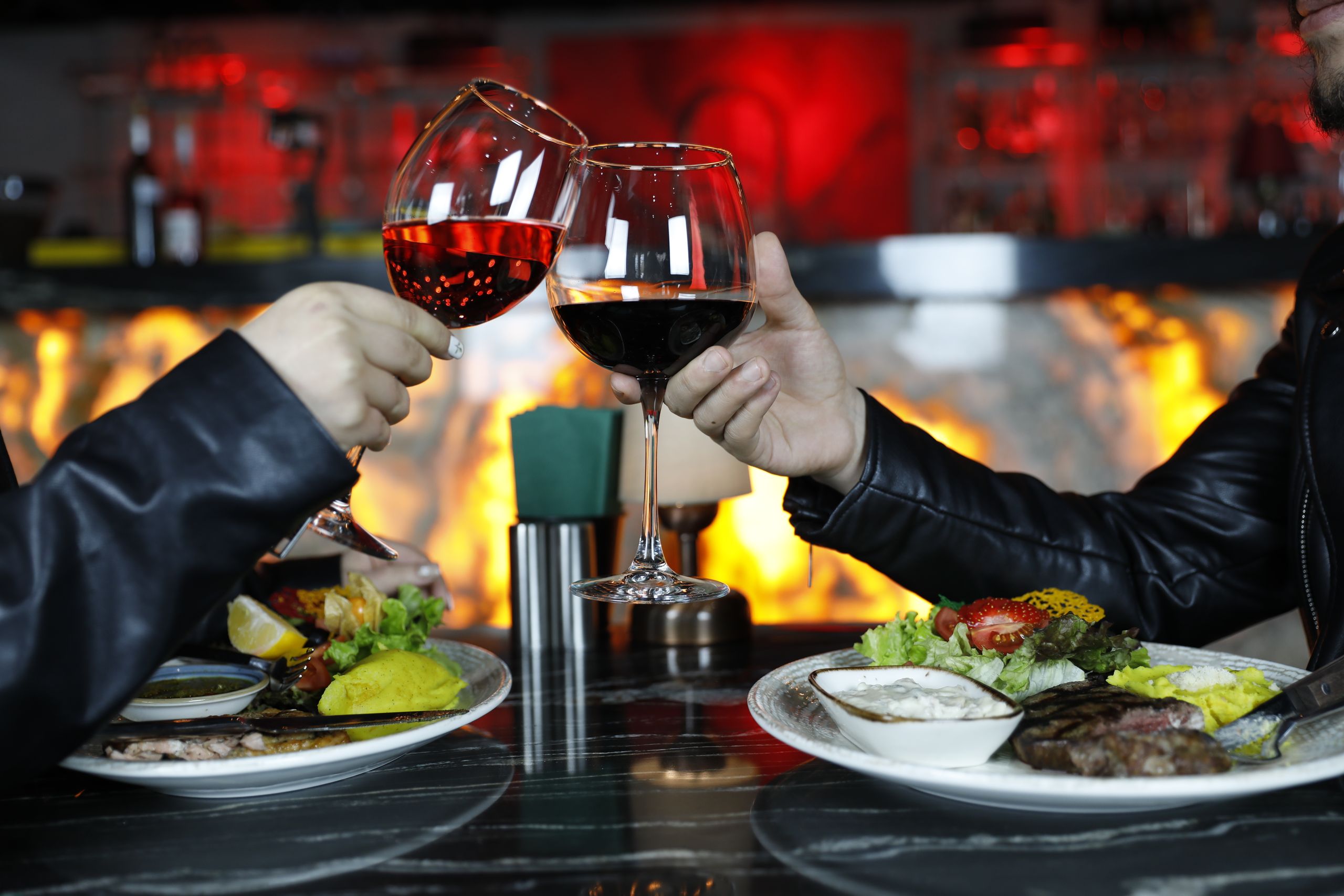 A couple enjoying a romantic dinner with red wine in a dimly-lit restaurant.