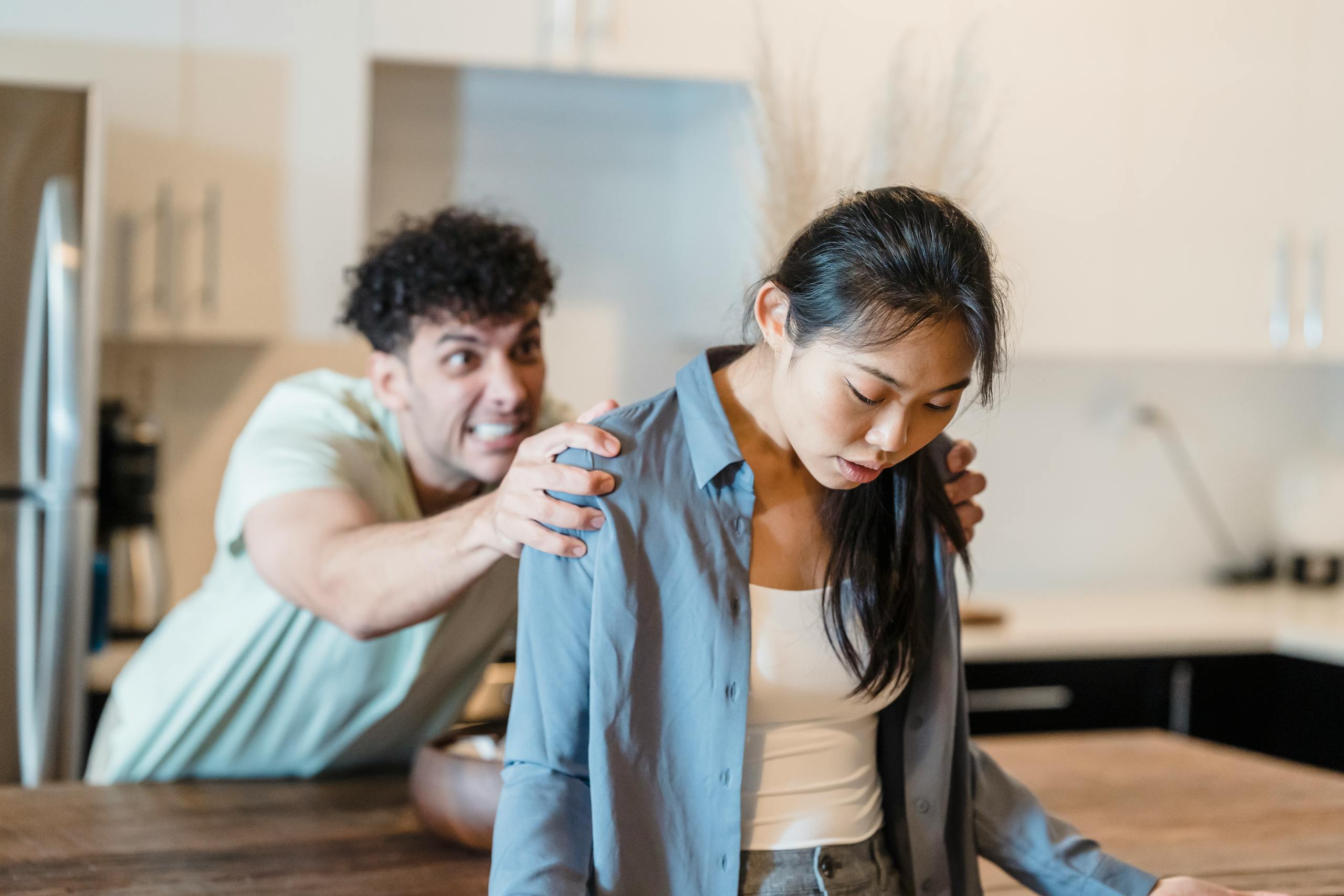 A couple experiencing emotions and tension in a modern kitchen setting.