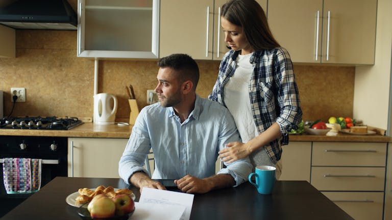 A couple having a serious discussion over breakfast papers in a modern kitchen.