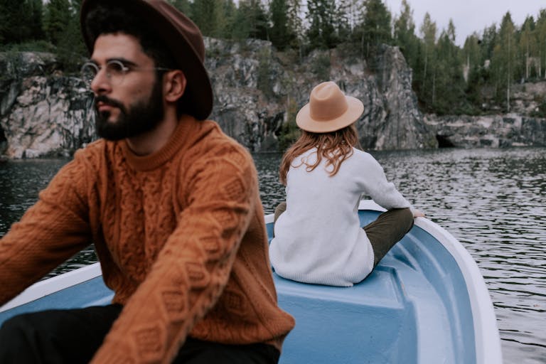 A couple on a boat exploring a scenic lake surrounded by rocky cliffs and lush trees.