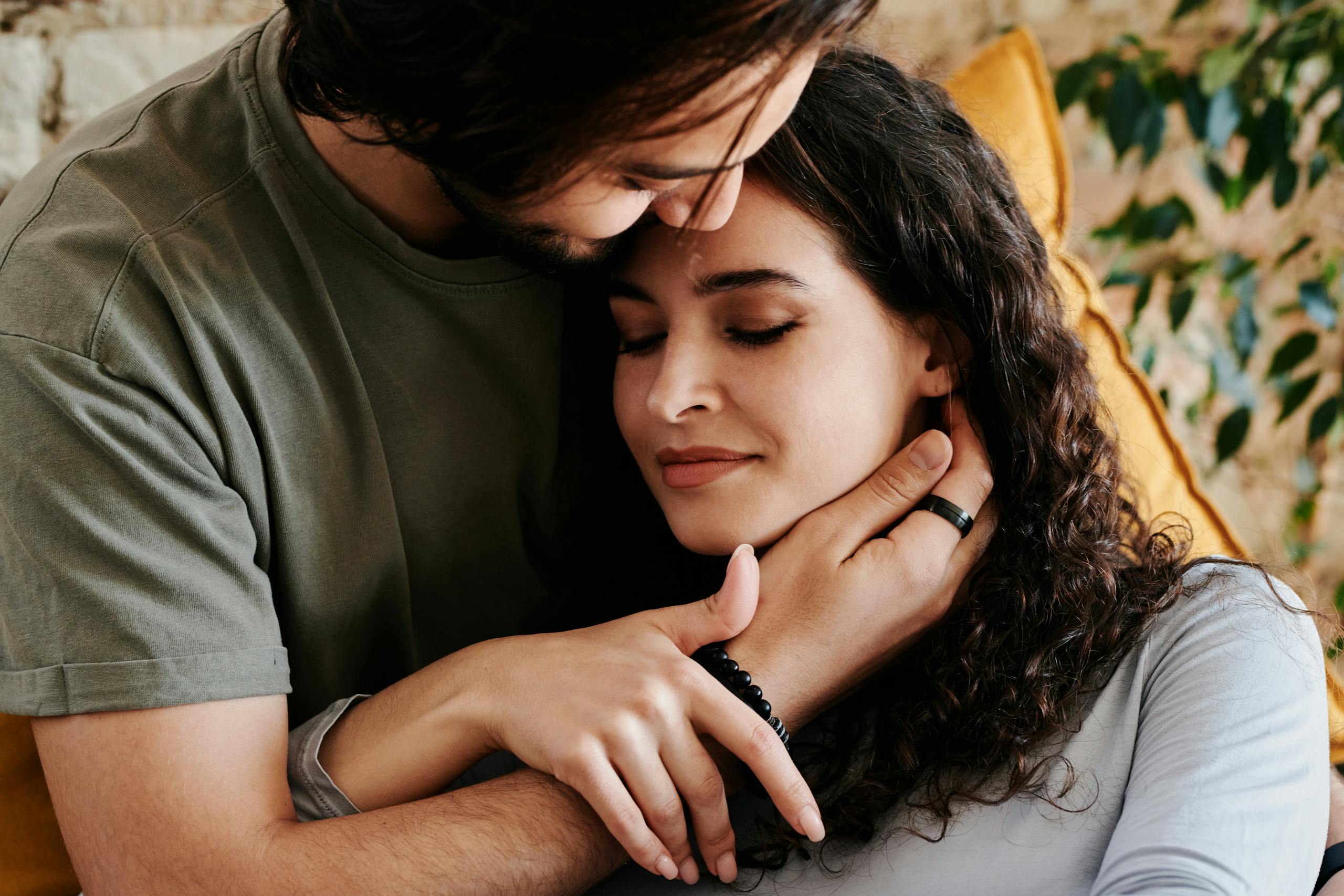 A couple shares a tender embrace, exuding warmth and love indoors.